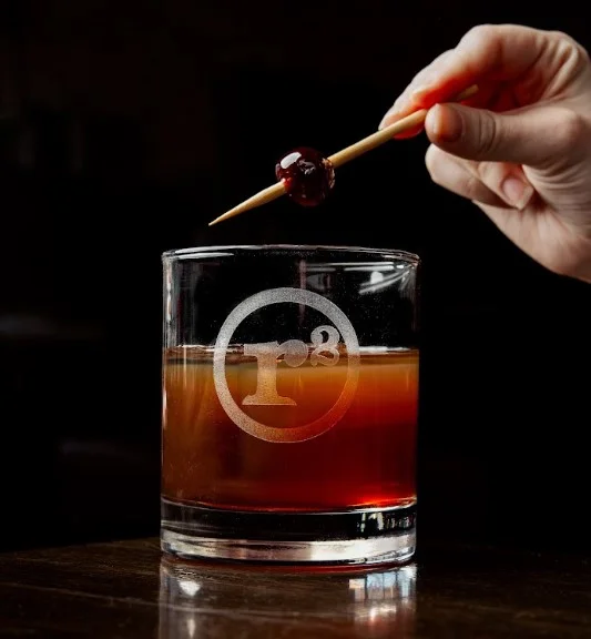 Craft cocktail with cherry garnish at a modern bar