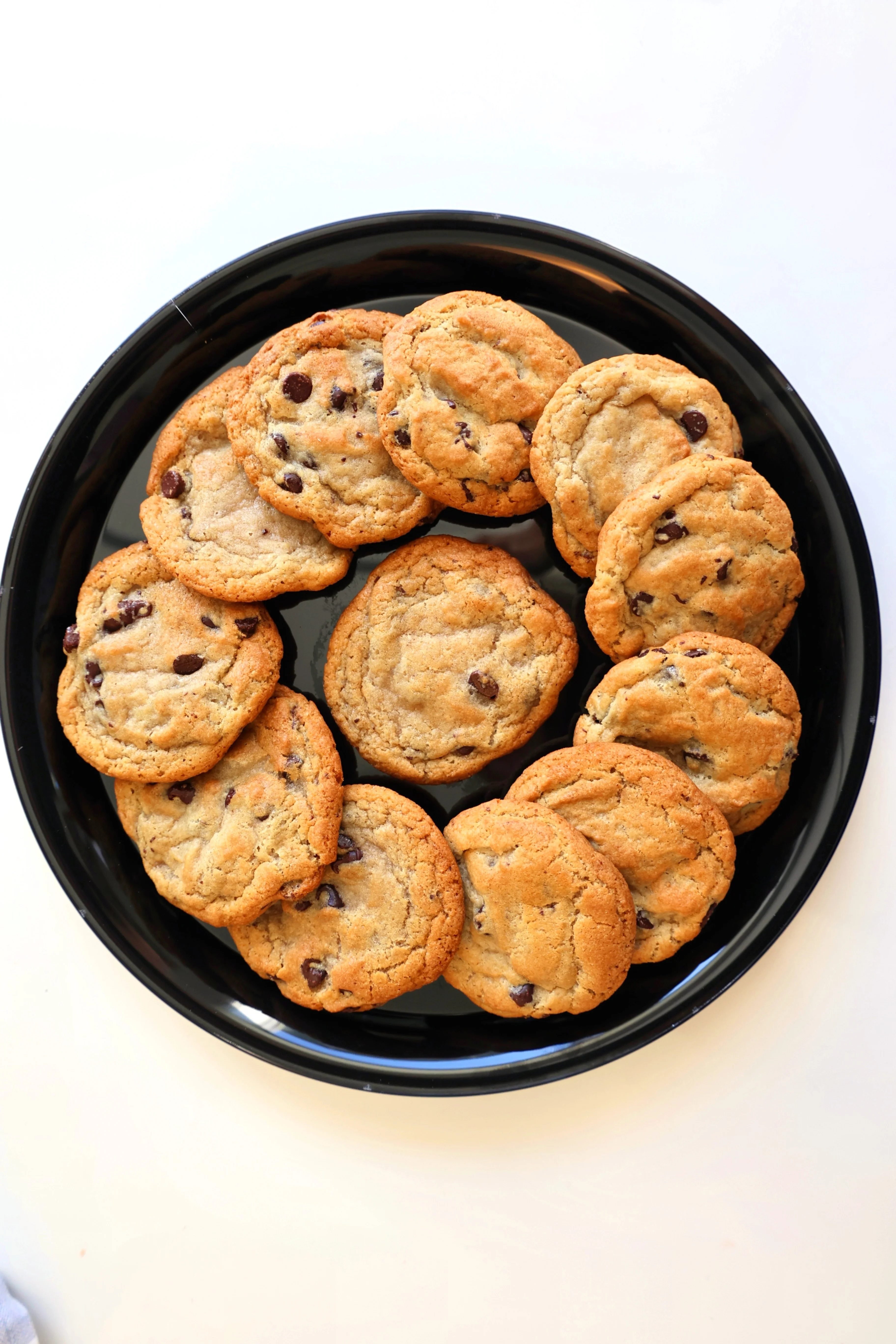 Freshly baked chocolate chip cookies on a black plate