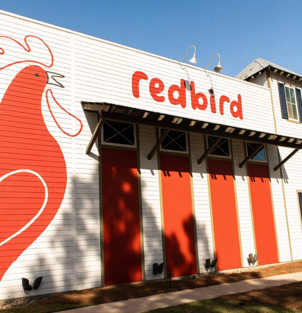 Exterior of Redbird restaurant with vibrant red chicken mural