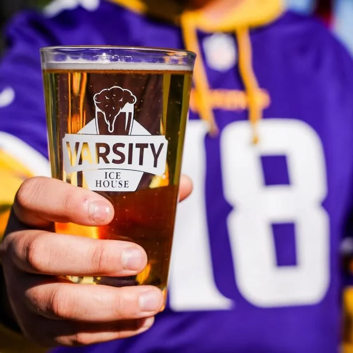 Person holding a glass of beer at a sports bar