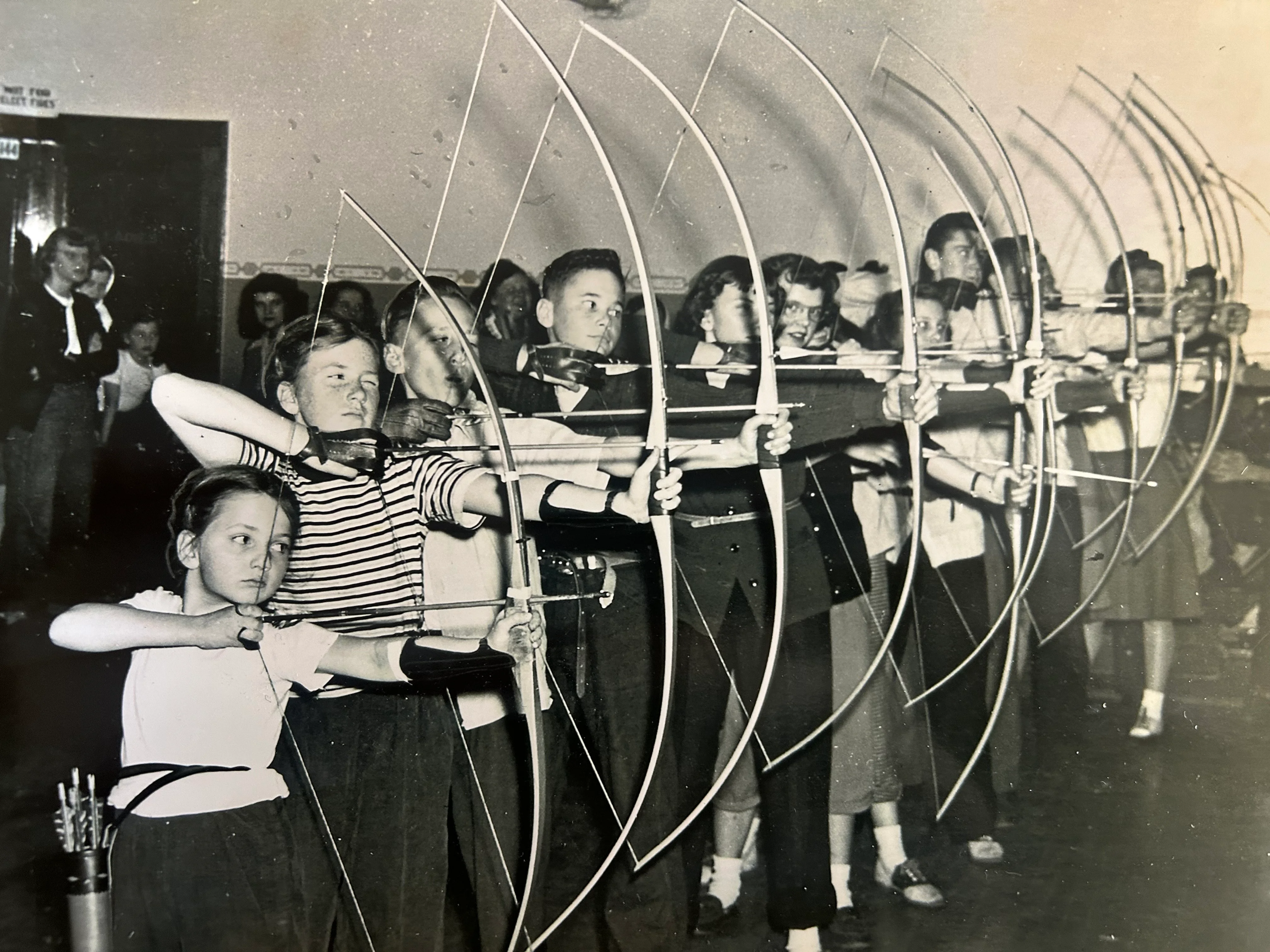 Group of children practicing archery indoors