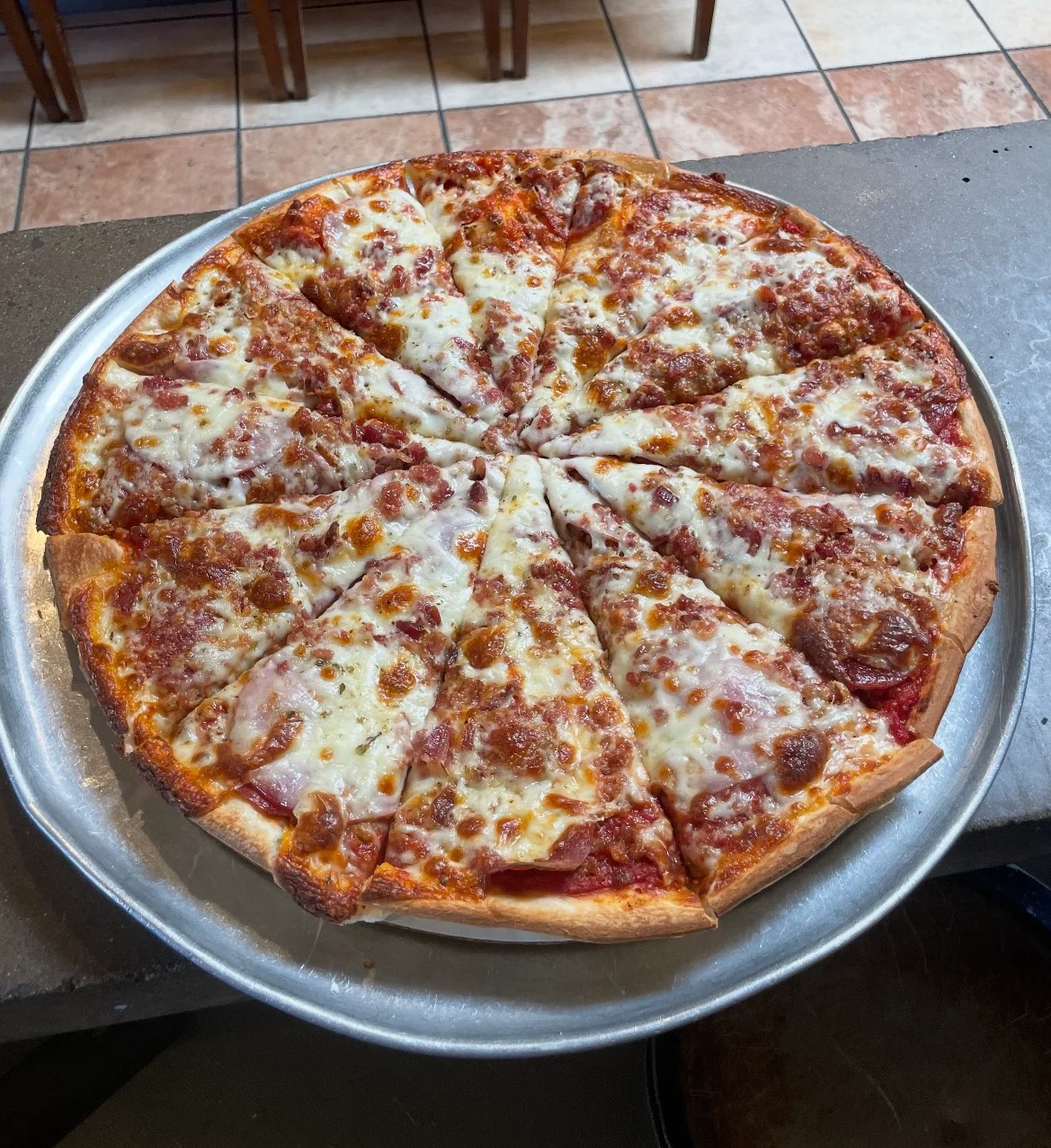 Cheese pizza served on a metal tray in a casual dining setting