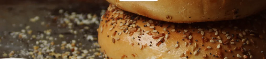 Freshly baked sesame bagels stacked on a baking sheet