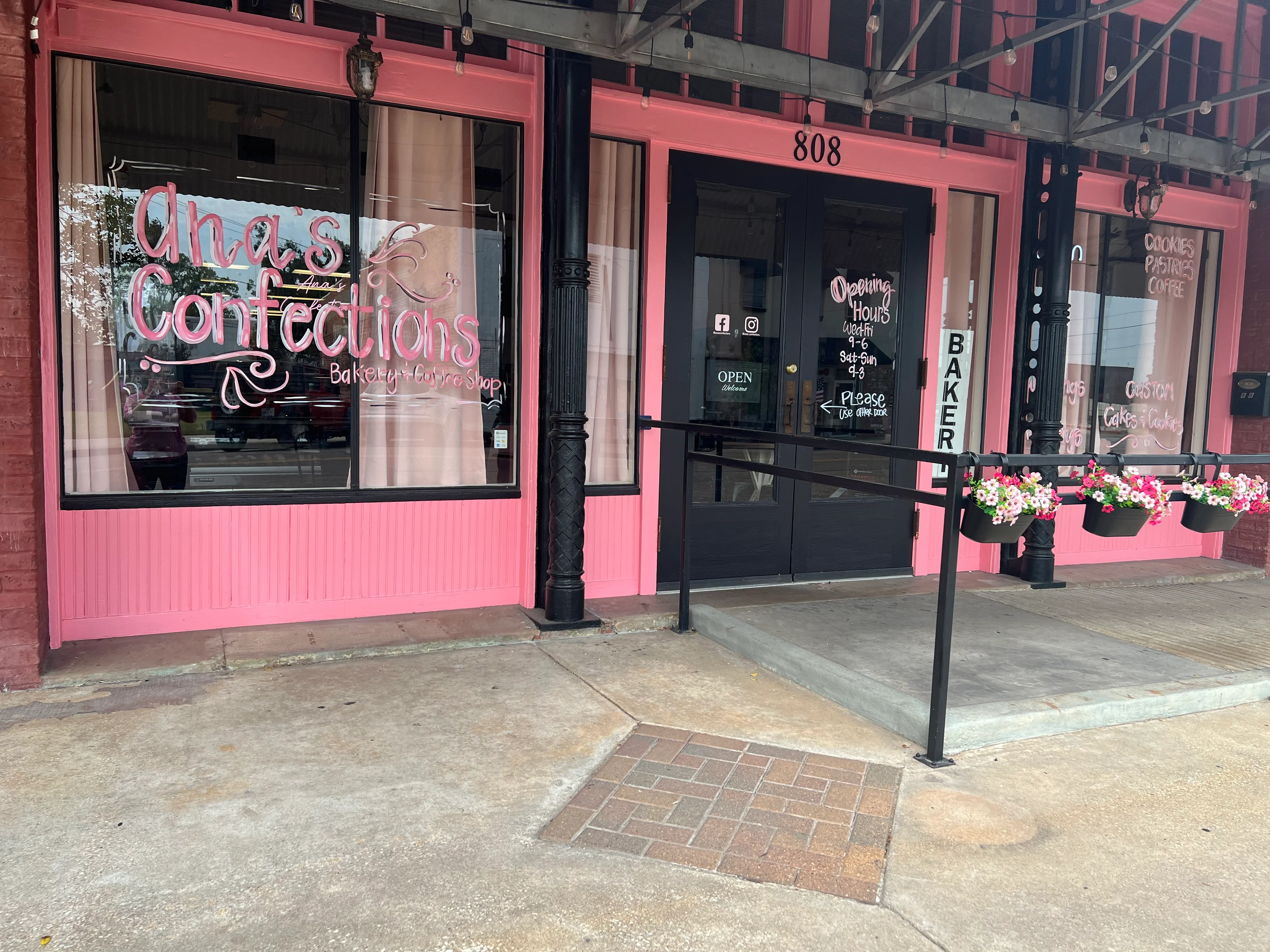Charming bakery storefront with pink accents and flower pots