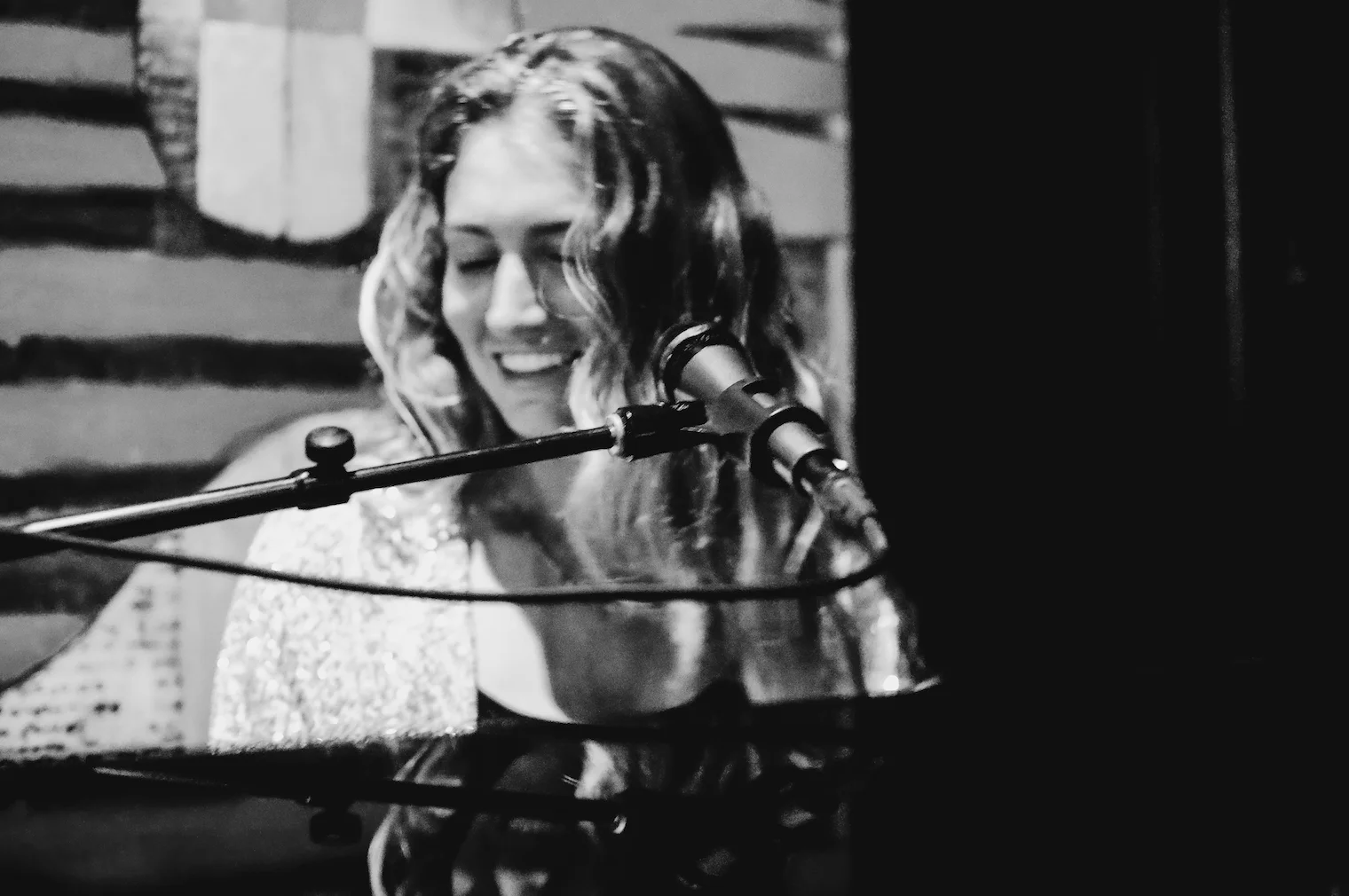 Musician performing at a piano with a microphone in a cozy venue