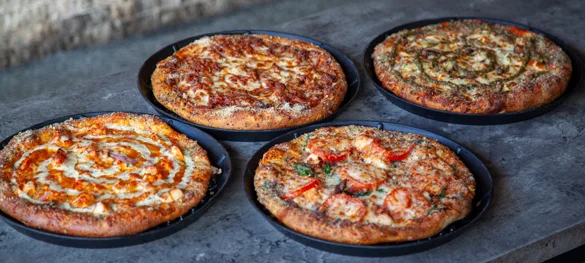 Four delicious pizzas on a rustic table