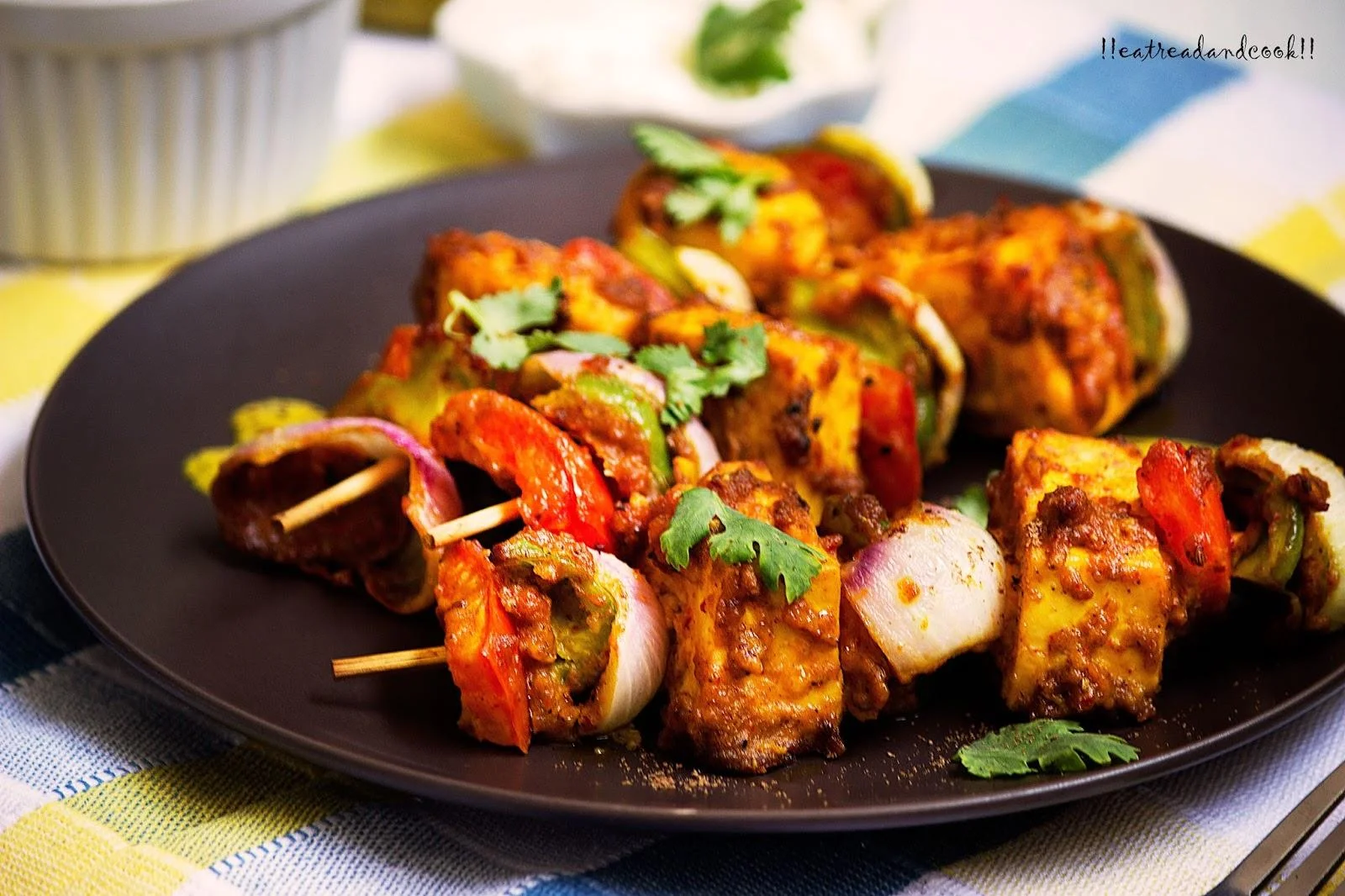 A colorful assortment of skewered paneer and vegetables, grilled to perfection and garnished with fresh herbs.