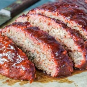 Sliced glazed meatloaf with a shiny tomato-based sauce.