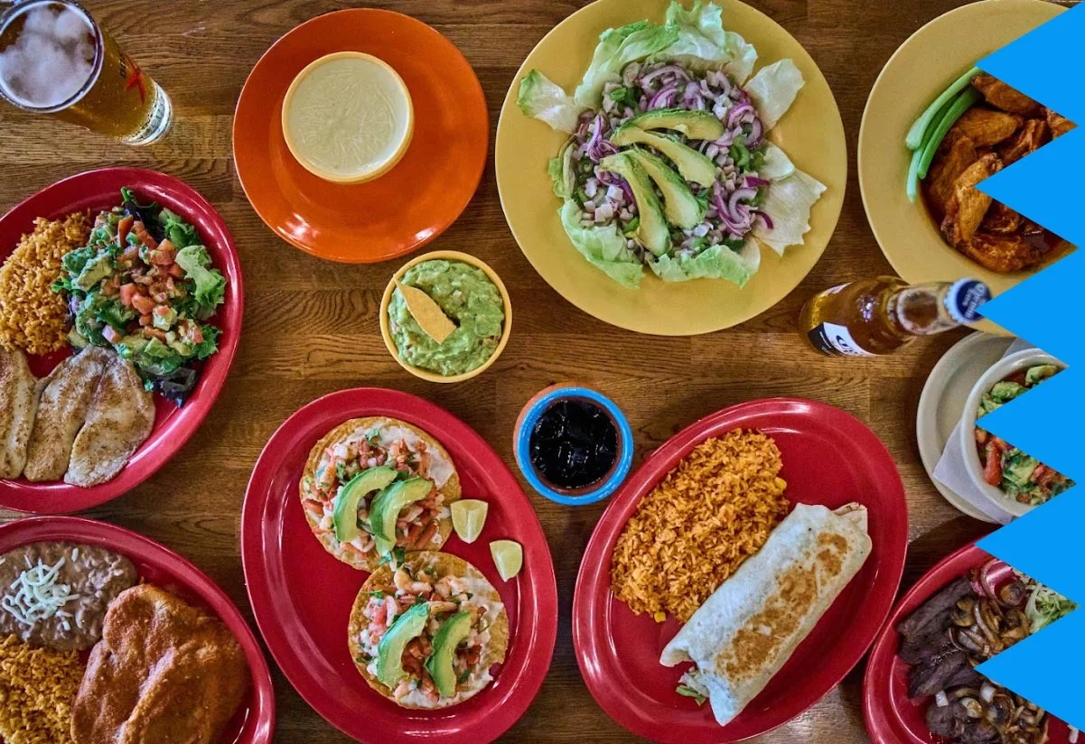 A plate with a burrito, rice, and sides of chips and guacamole.