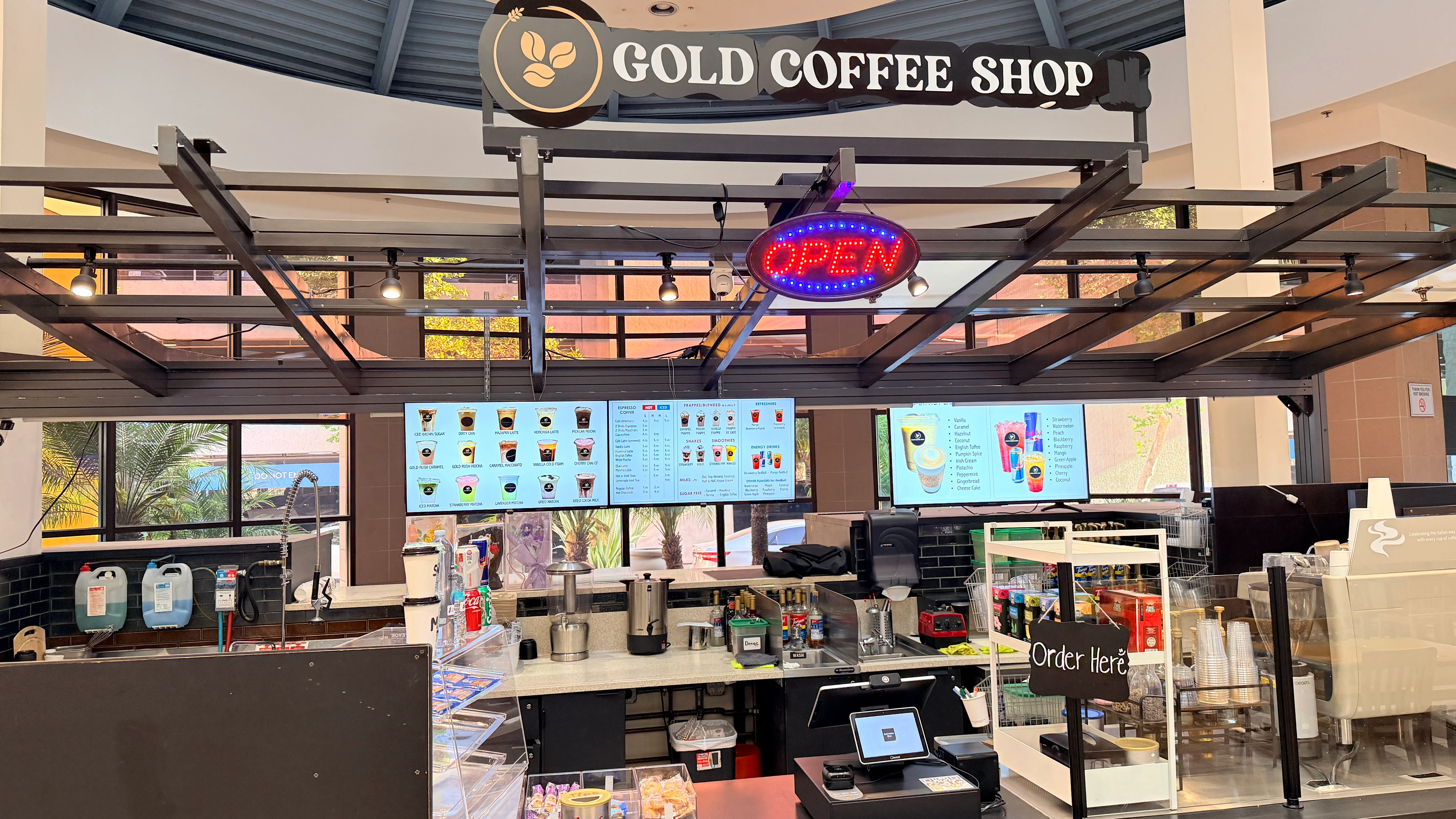 Interior of Gold Coffee Shop with menu displays and open sign.