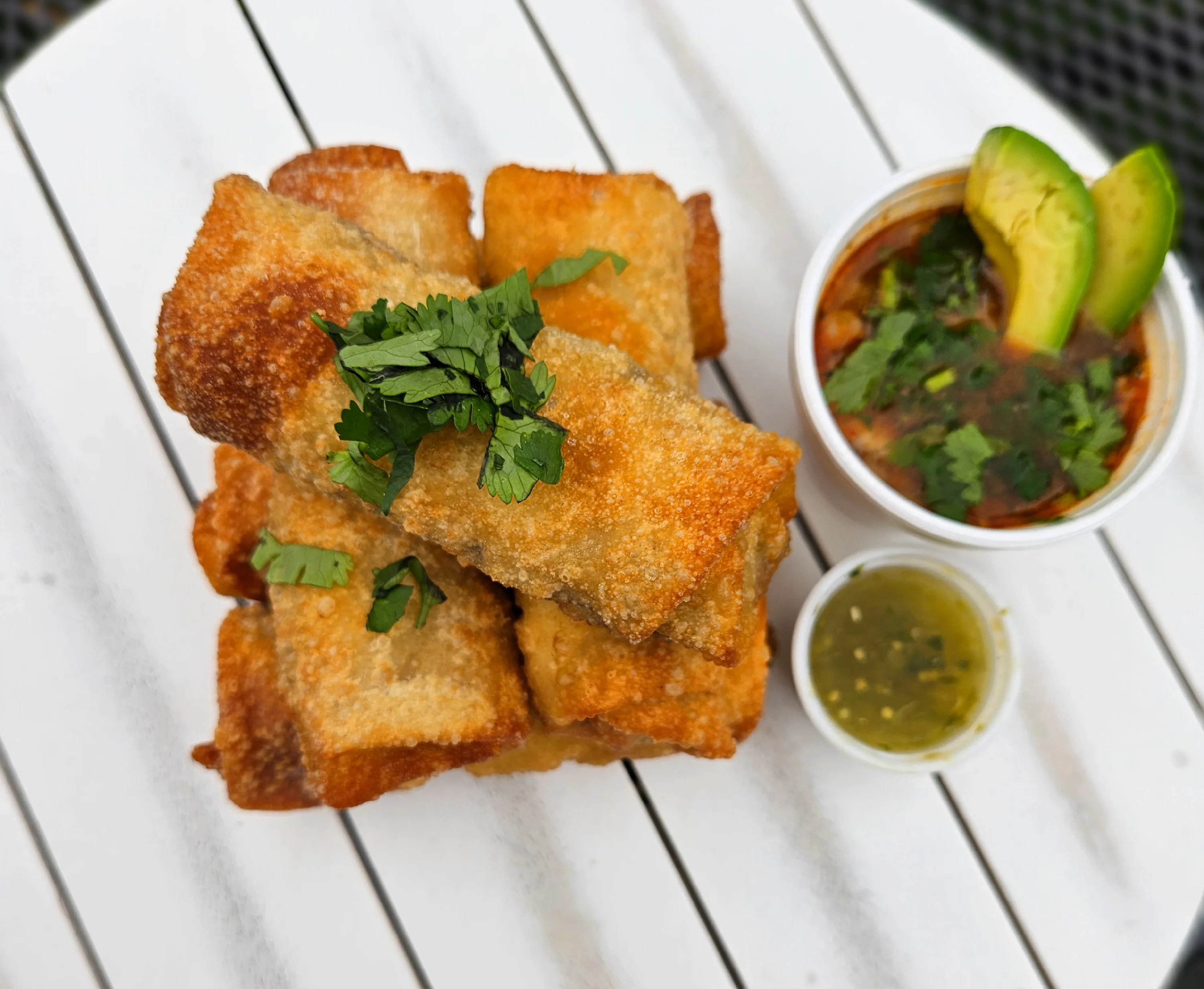 Crispy Mexican flautas served with salsa and avocado