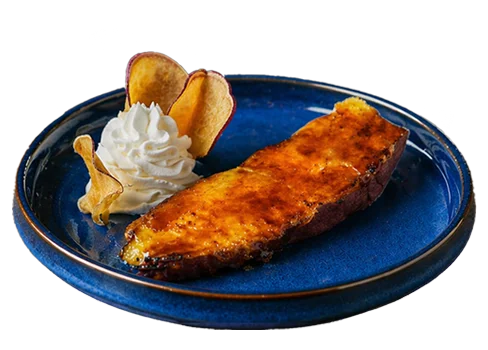 Two halves of a roasted sweet potato with a caramelized, golden-brown topping and a scoop of green tea ice cream on a bold blue plate.