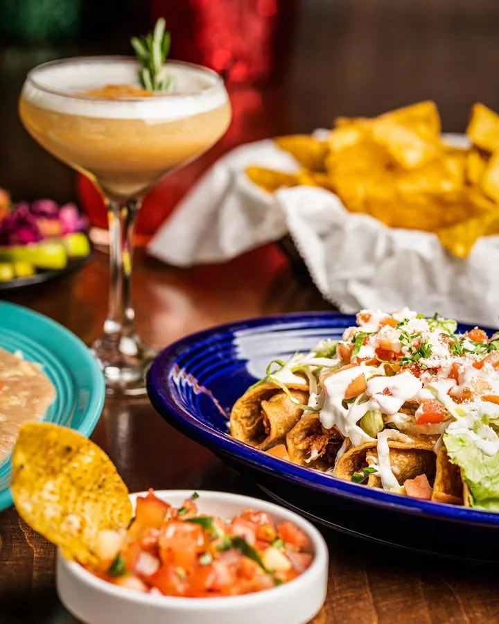 Plate of Mexican taquitos topped with fresh salsa and sour cream