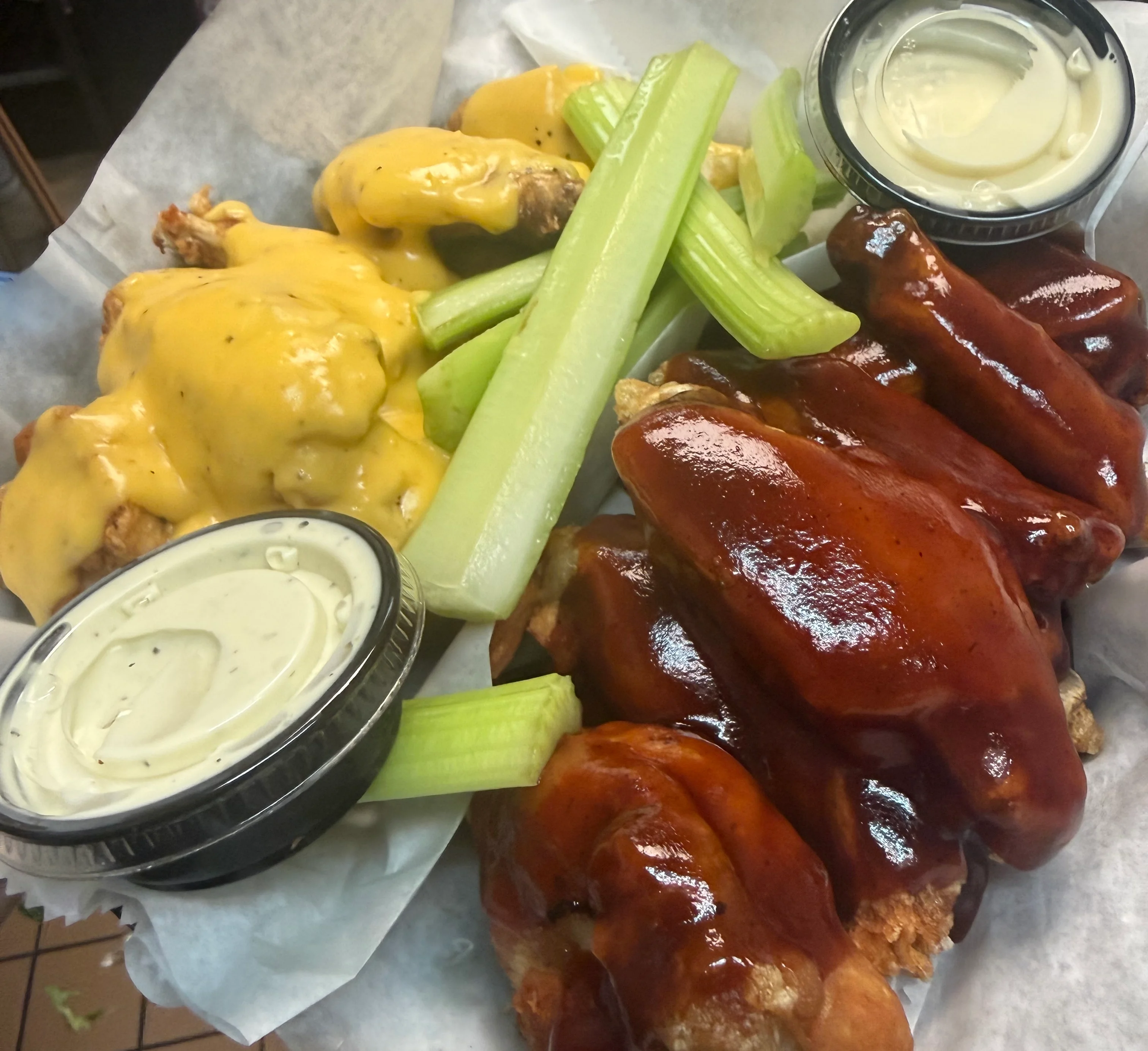 Plate of BBQ chicken wings with cheese sauce and celery sticks