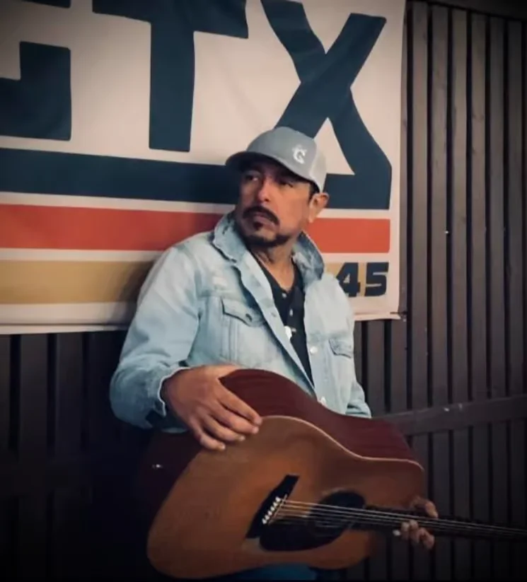 Musician posing with guitar in a rustic setting