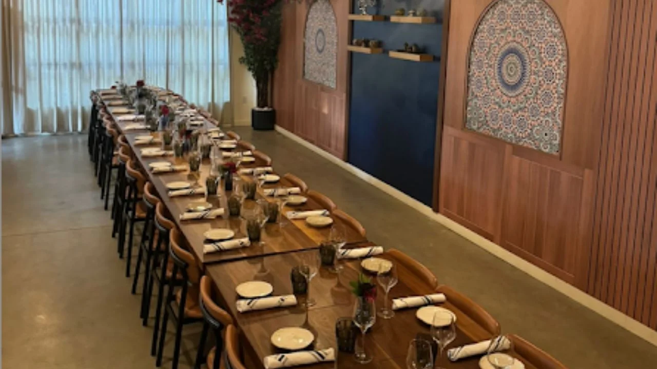 Elegant restaurant dining setup with long wooden table and floral decor