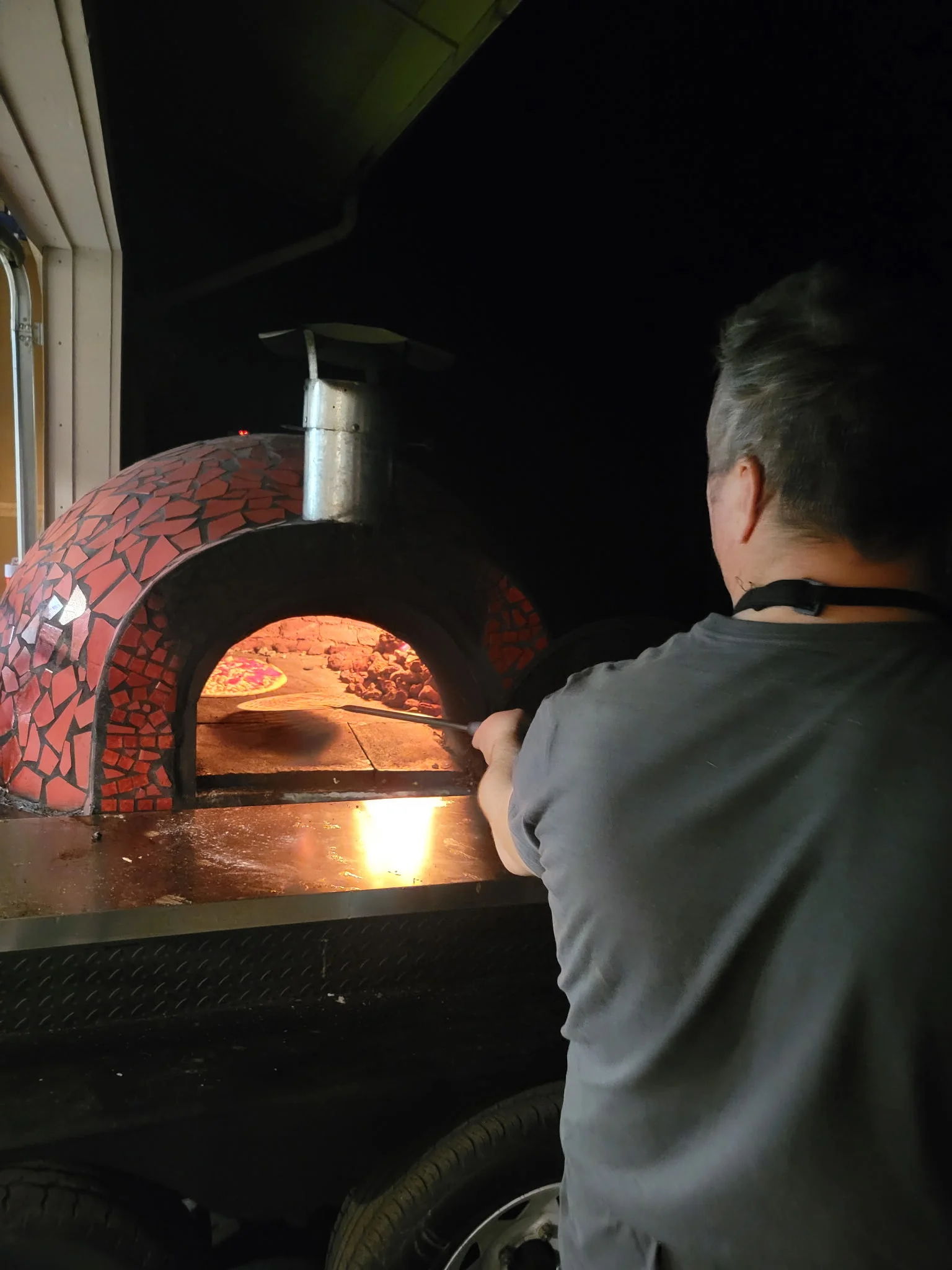 Chef using a pizza peel in a wood-fired oven