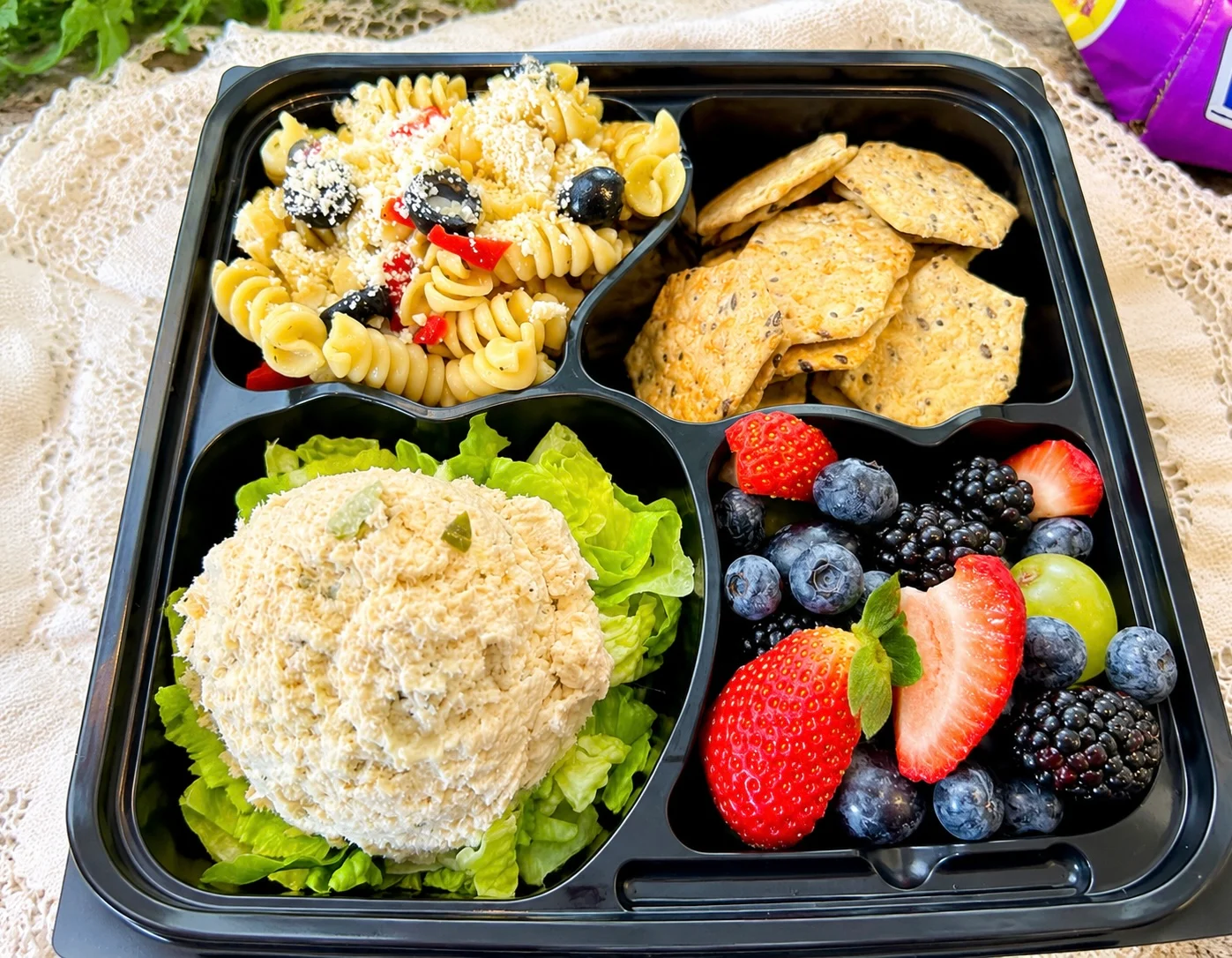 Colorful Mediterranean lunch box with pasta salad and fresh fruits