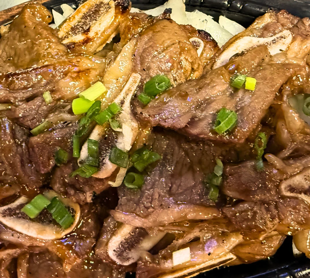 Grilled beef slices topped with green onions on a bed of rice.