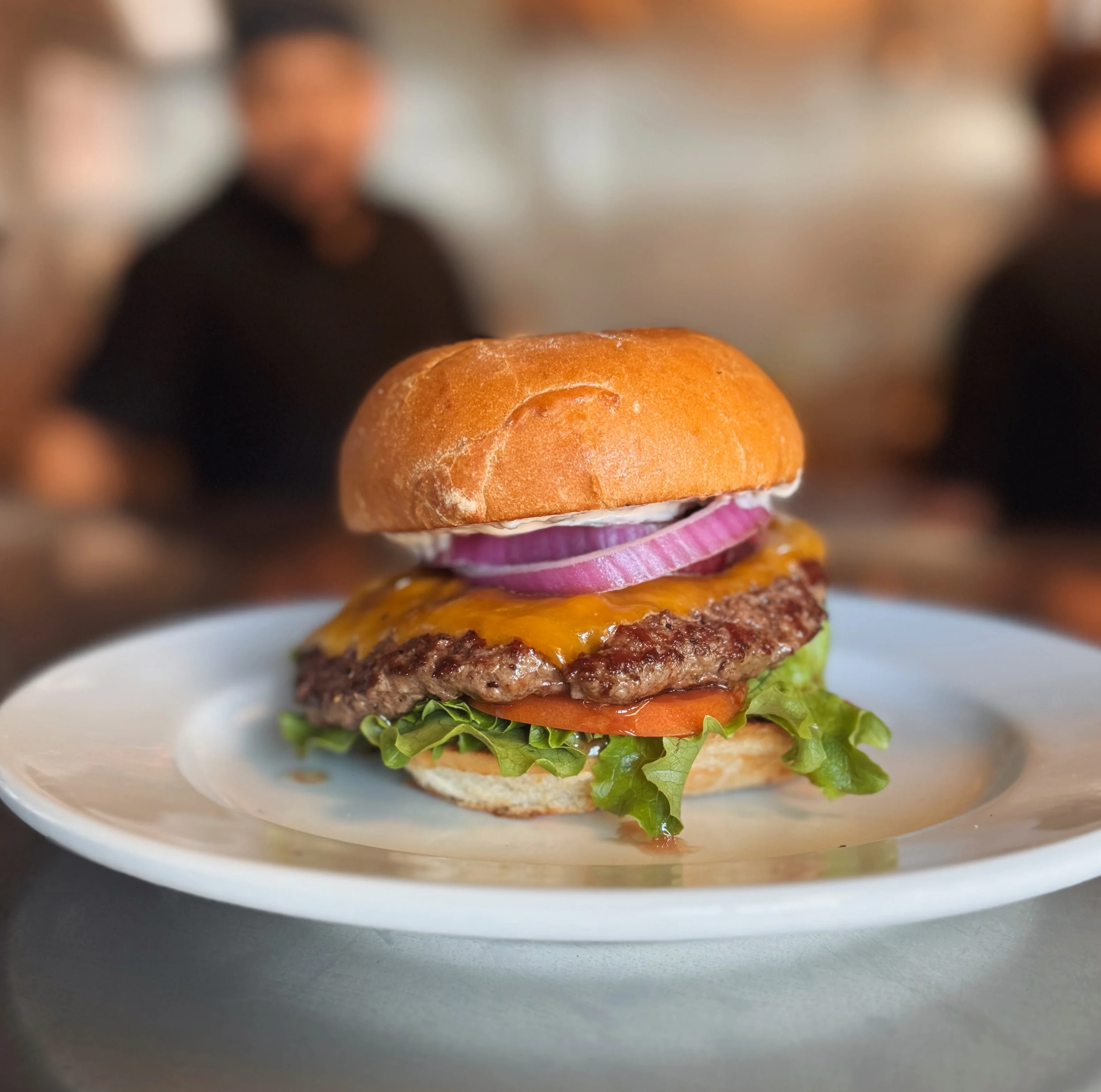 Juicy cheeseburger with lettuce and onion in a restaurant kitchen