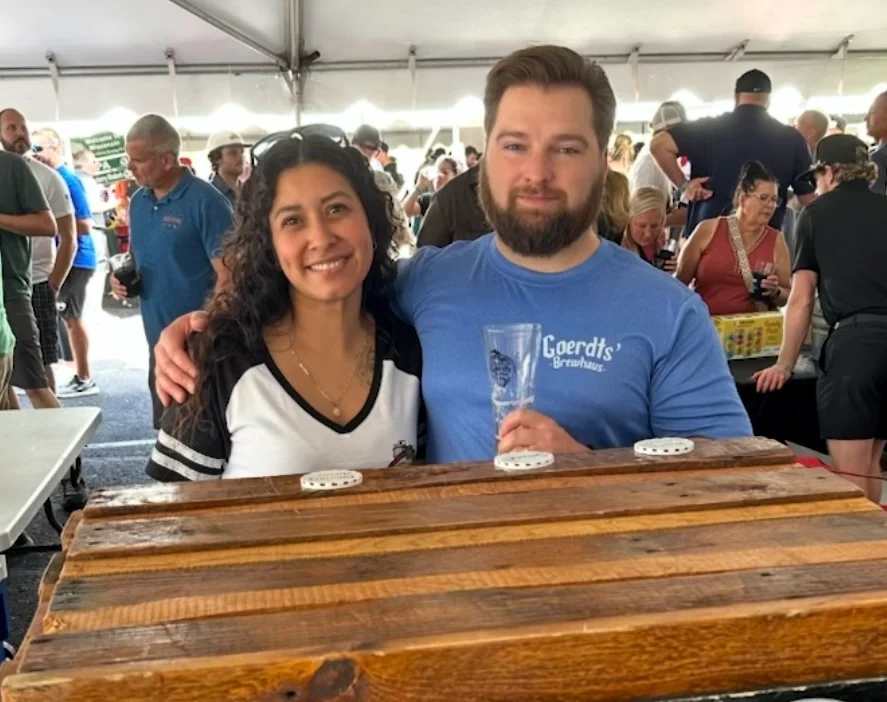 Two friends enjoying a craft beer festival under a tent