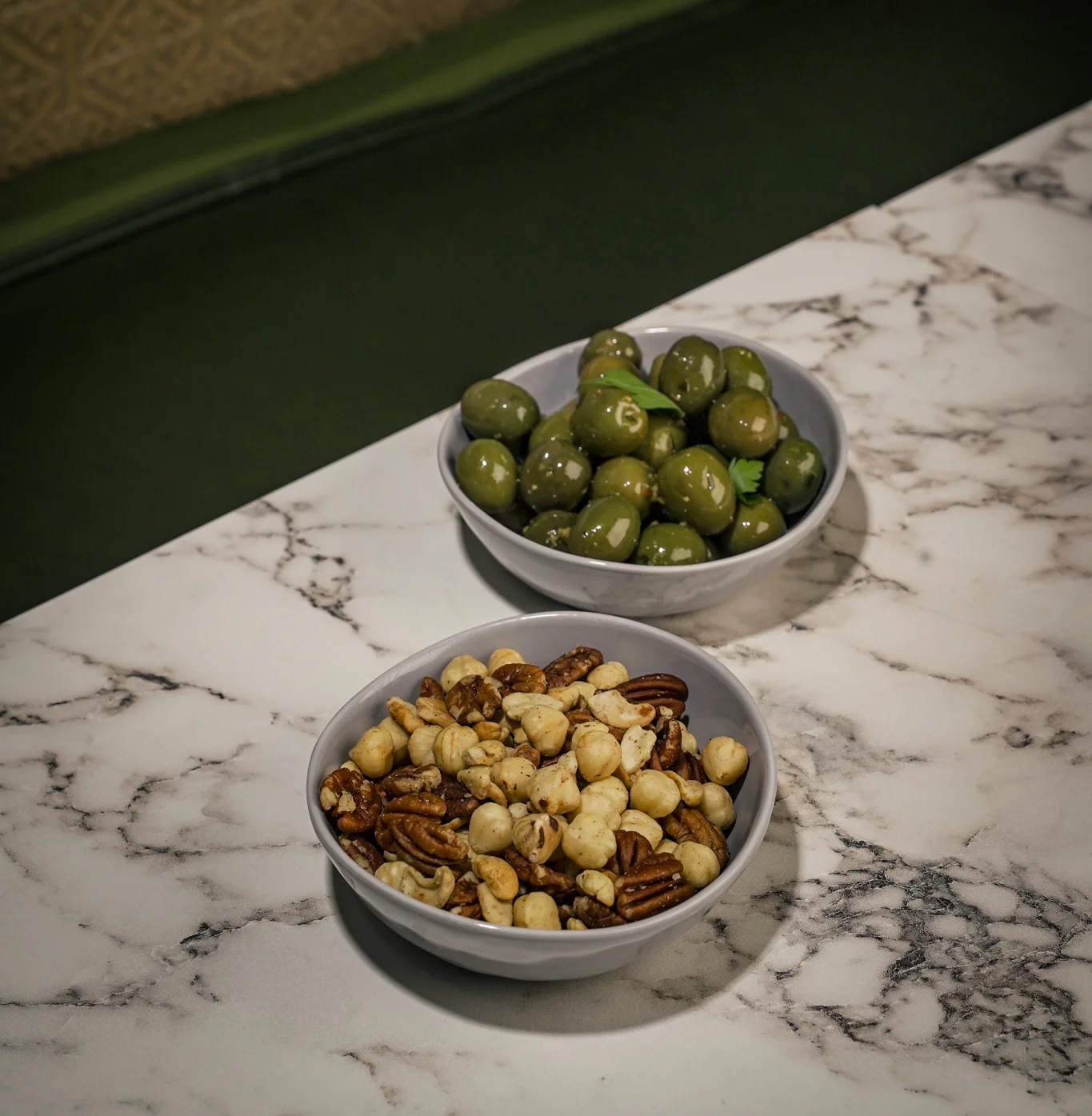 Mediterranean olives and mixed nuts in bowls on a marble table