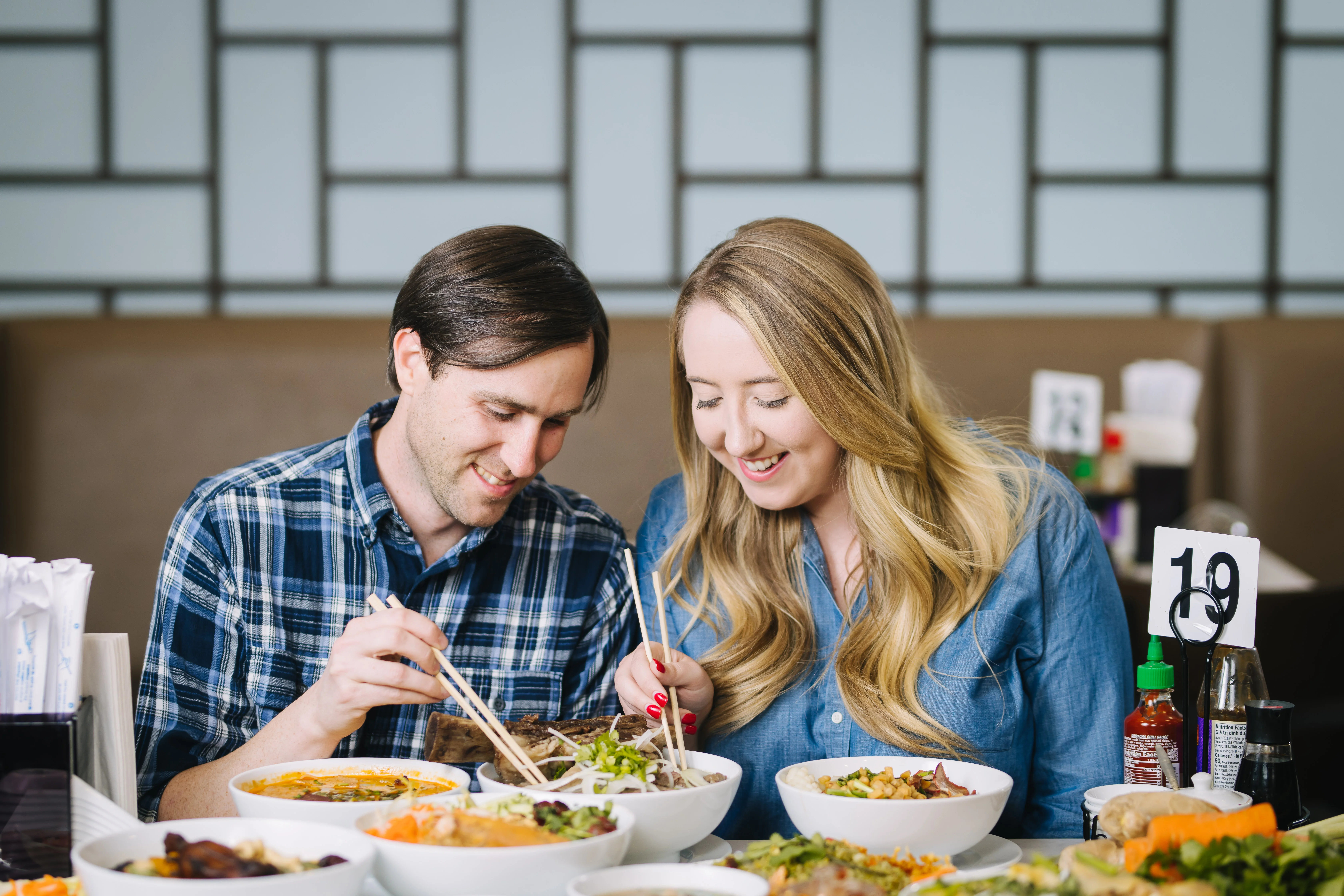 Couple enjoying a meal together with bowls of food and chopsticks.