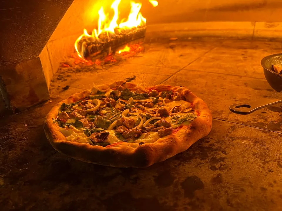 Wood-fired Margherita pizza baking in a traditional oven