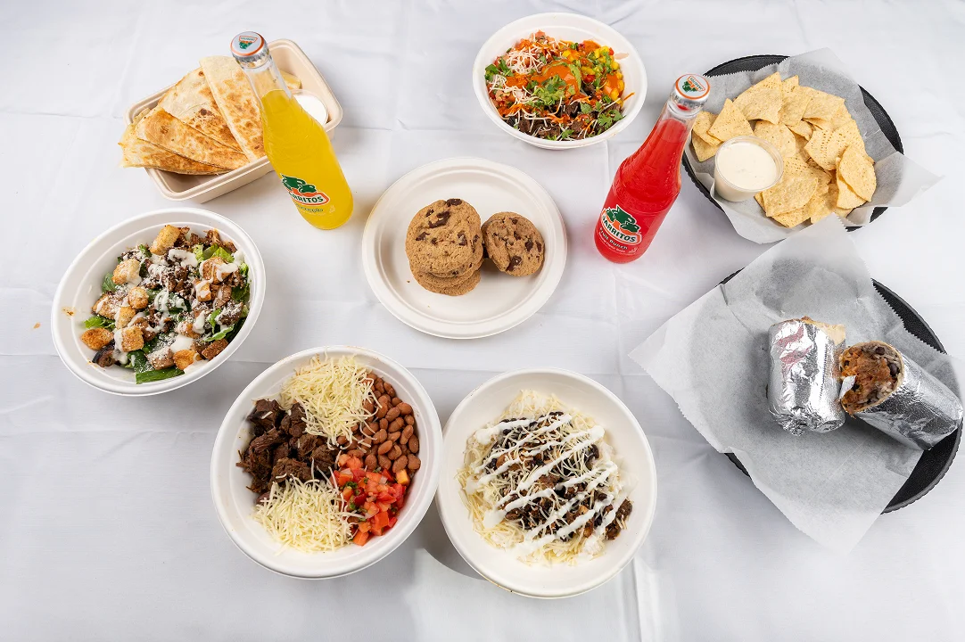 Four triangular slices of golden-brown cheese quesadillas served in a container next to a small cup of sour cream or white sauce.