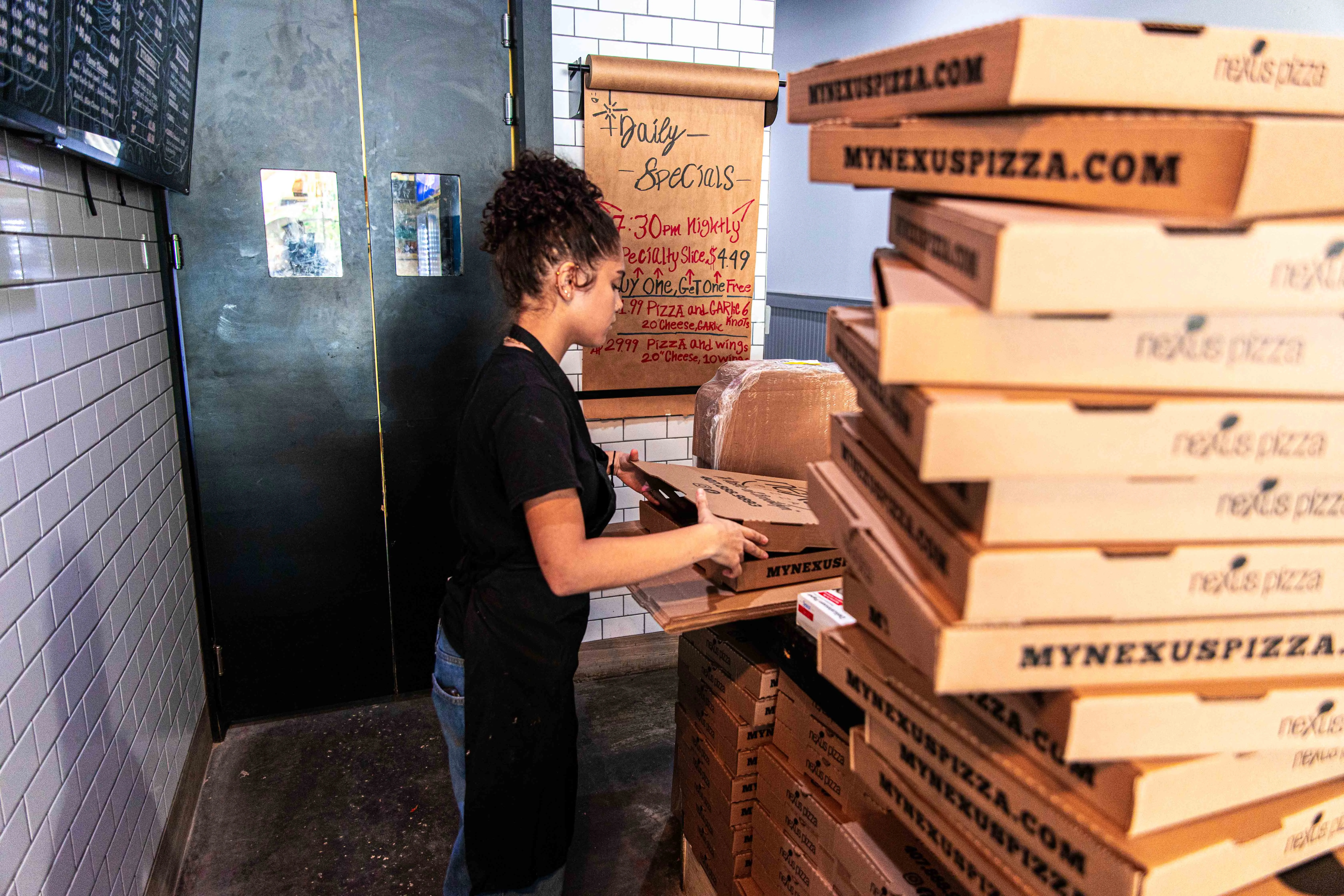 Employee preparing pizza boxes in a bustling pizzeria