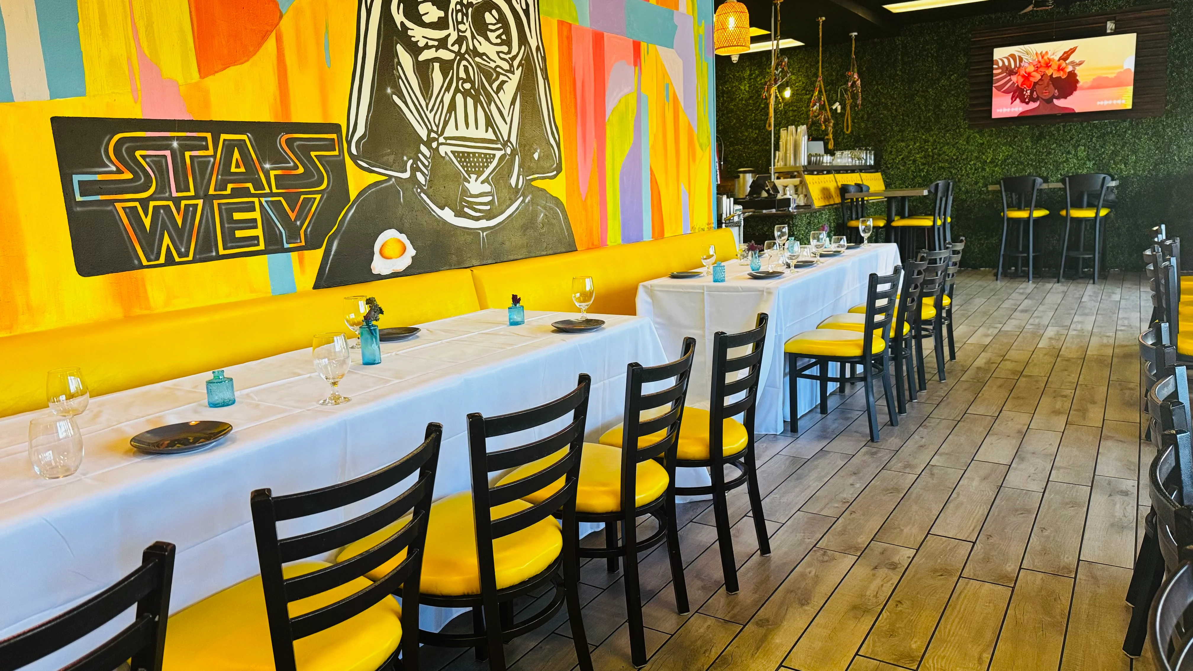 Vibrant restaurant interior with colorful mural and yellow seating