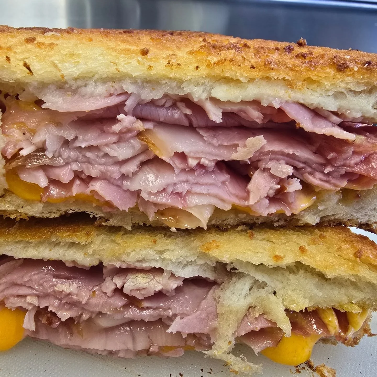 A close-up of a layered sandwich, featuring slices of ham and melted cheese between toasted bread.