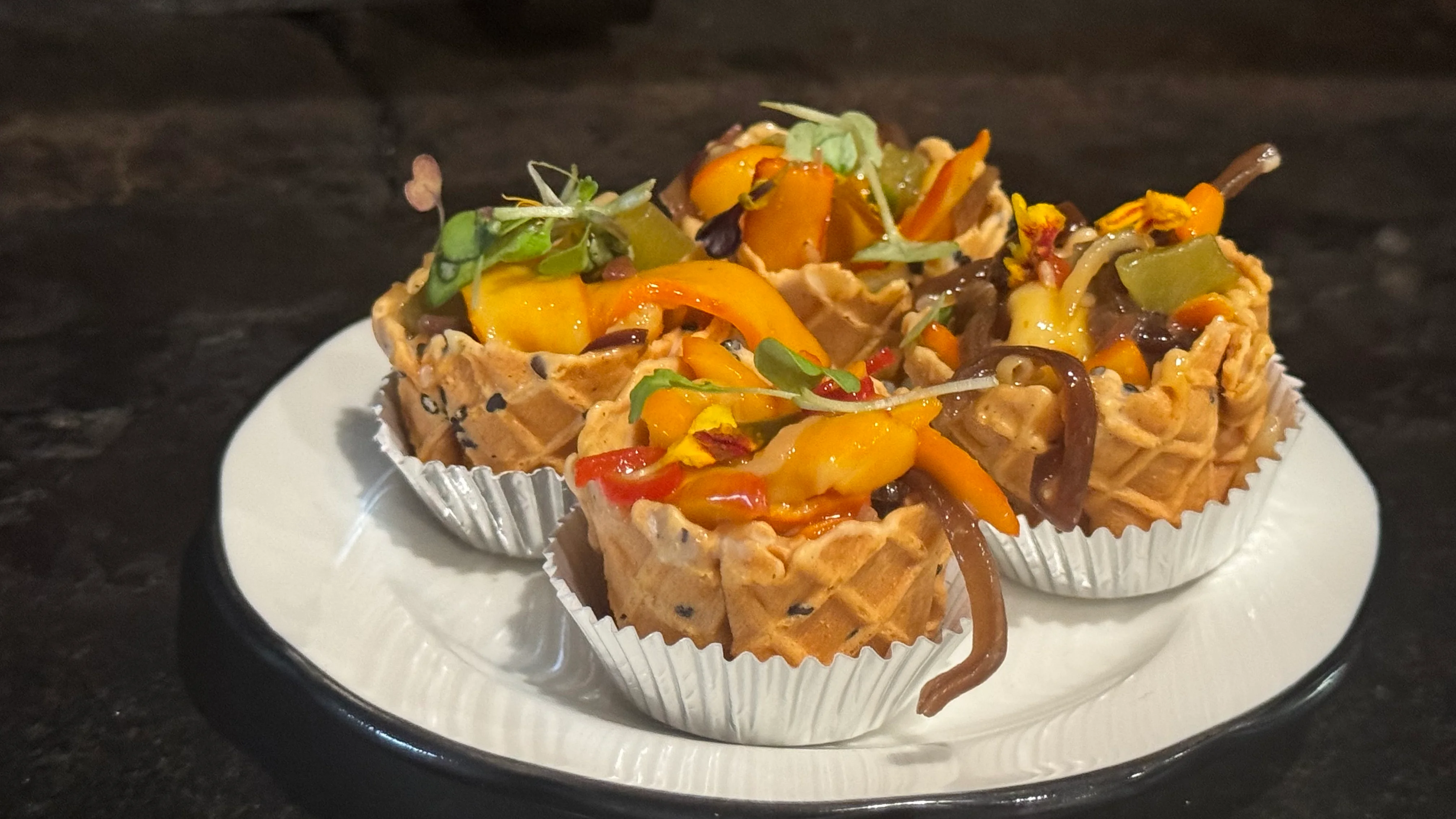 Vegetable salad presented in individual waffle cups as part of a catering spread