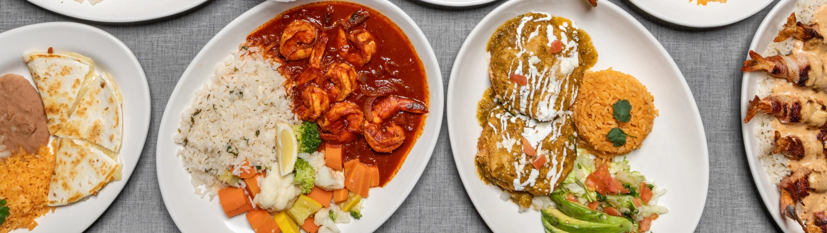 Colorful Mexican feast with tacos, enchiladas, and shrimp dish