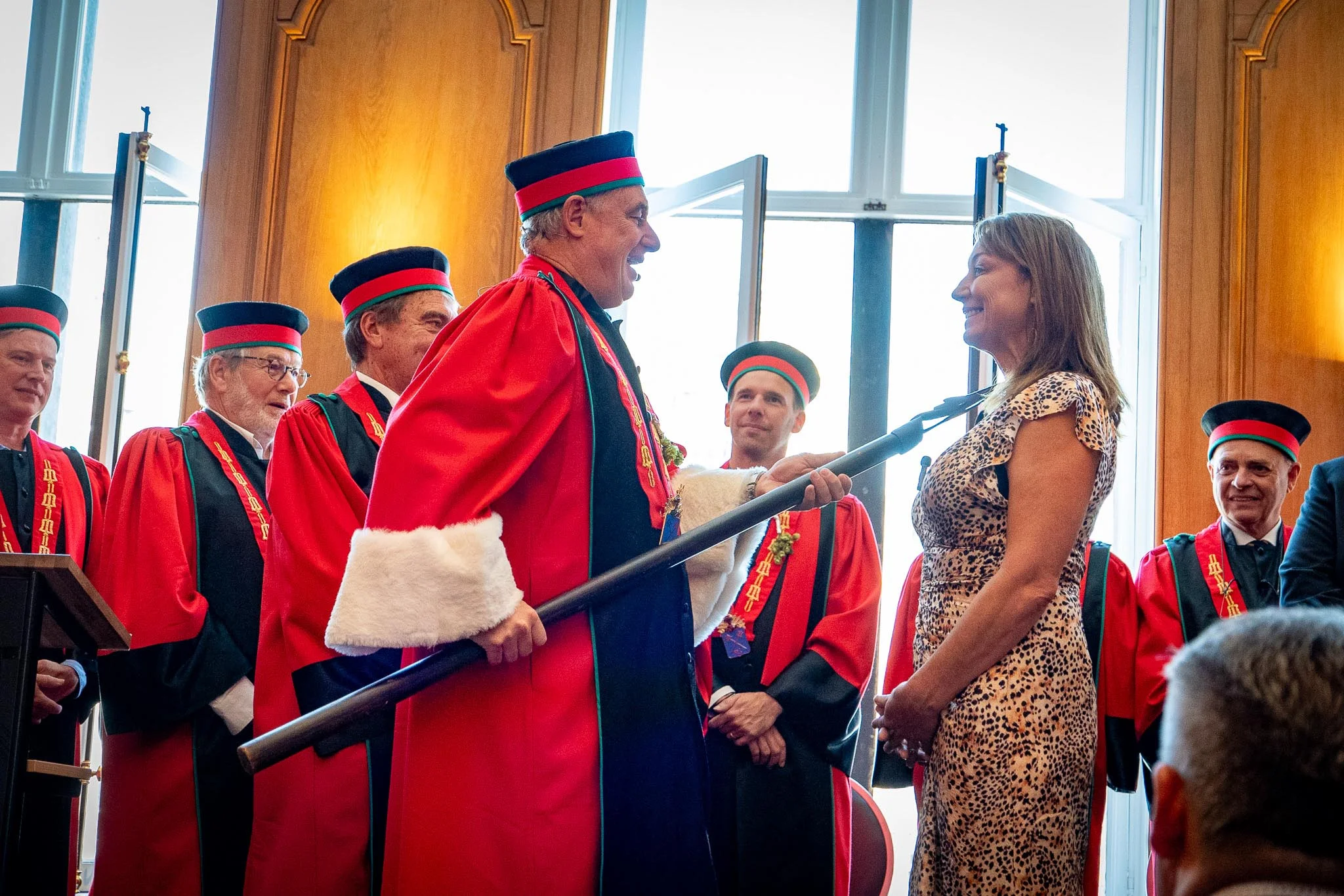 Ceremonial event with participants in traditional academic robes and regalia.