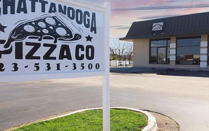 A sign for a pizza restaurant showing a cartoon image of a slice of pizza with the restaurant's name and phone number.
