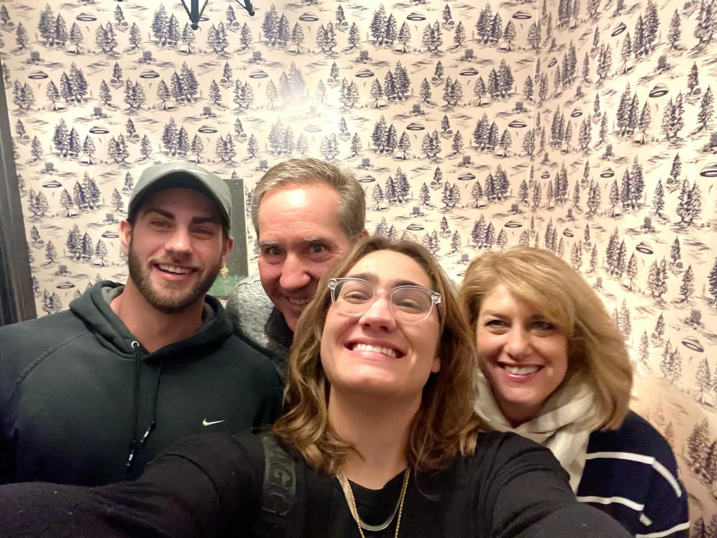 Group selfie in a cozy restaurant setting with patterned wallpaper
