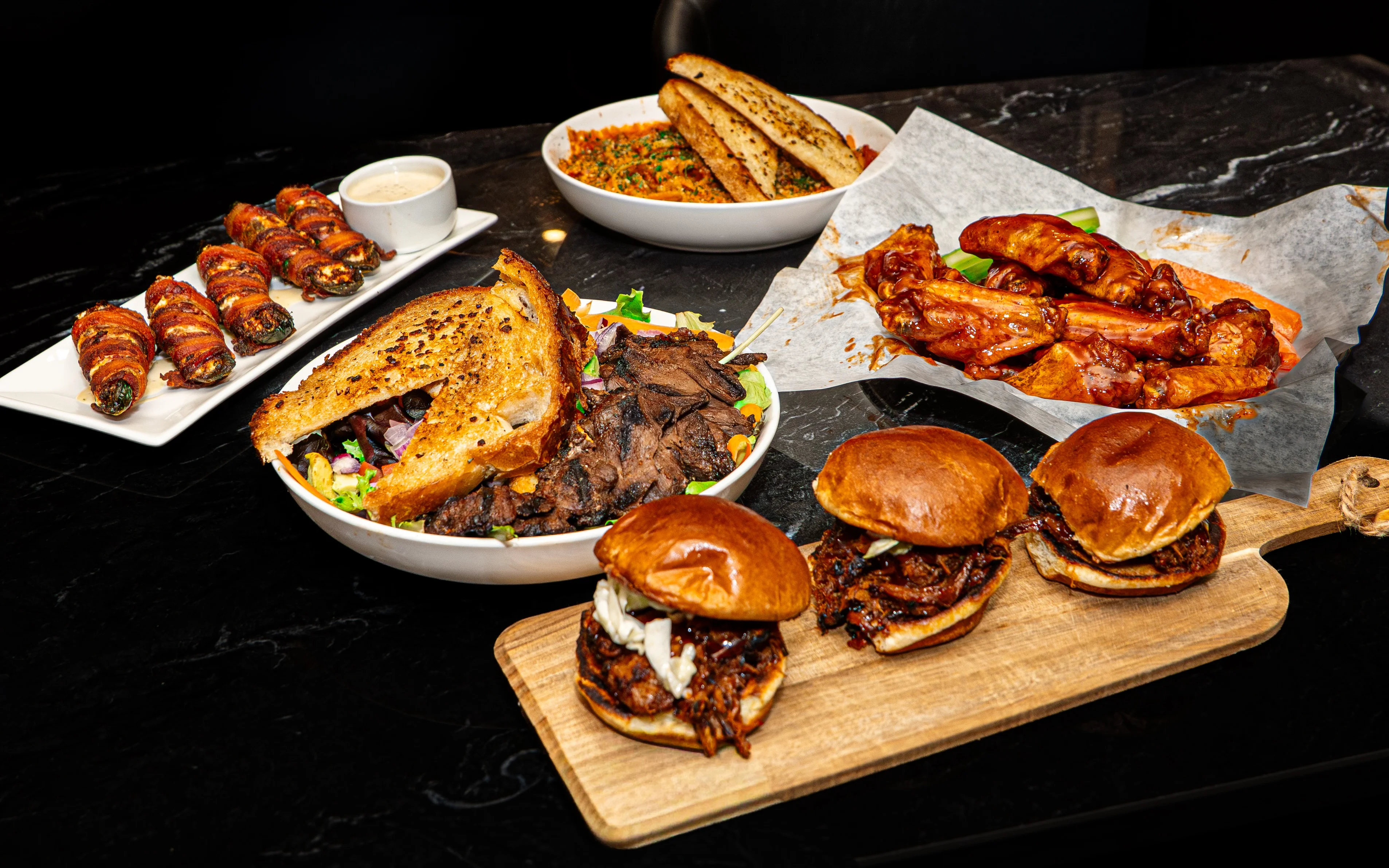 Platter of American BBQ with wings, sliders, and jalapeño poppers