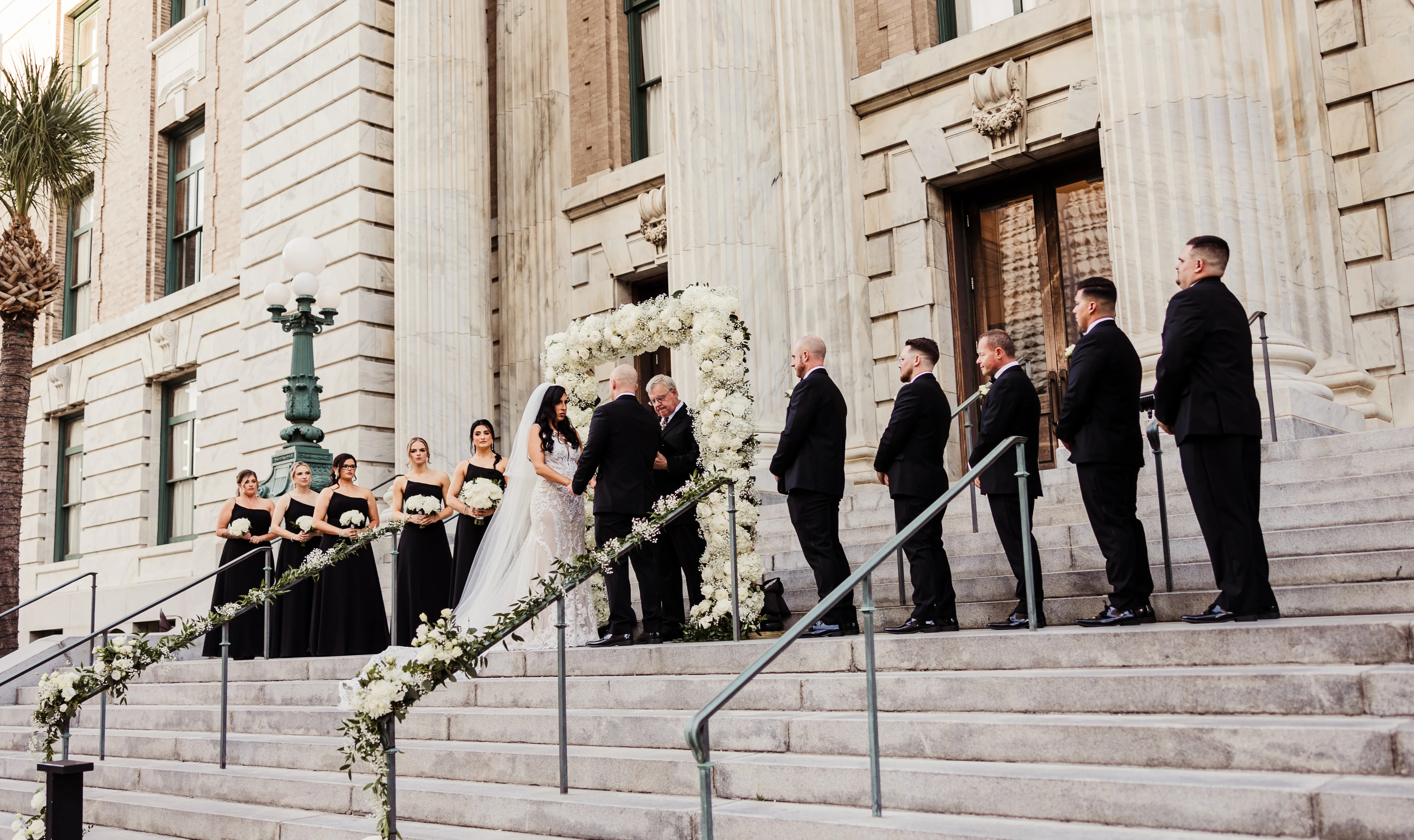 Outdoor wedding ceremony with floral arch and bridal party