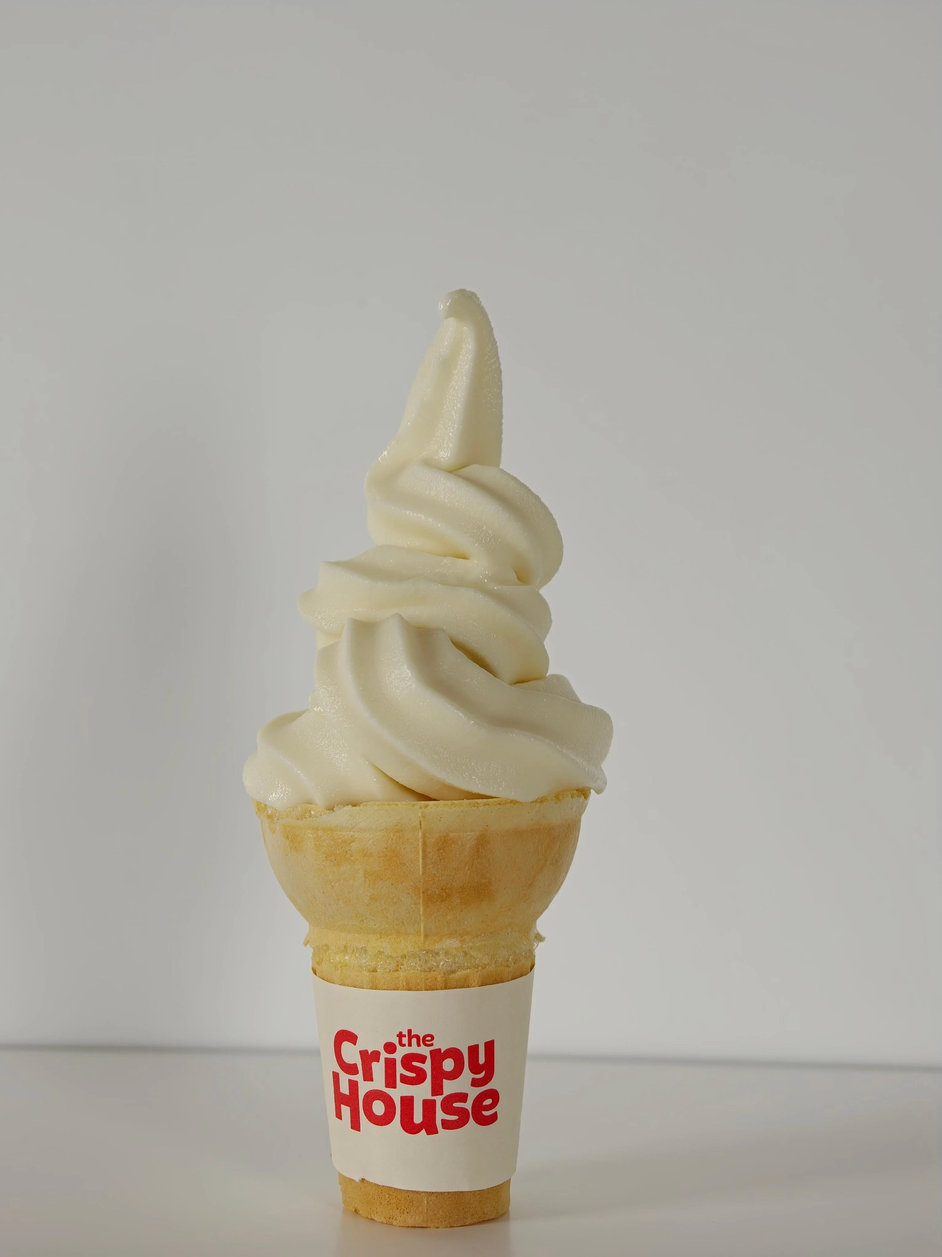 A soft-serve ice cream cone with a swirled top, served in a waffle cone.