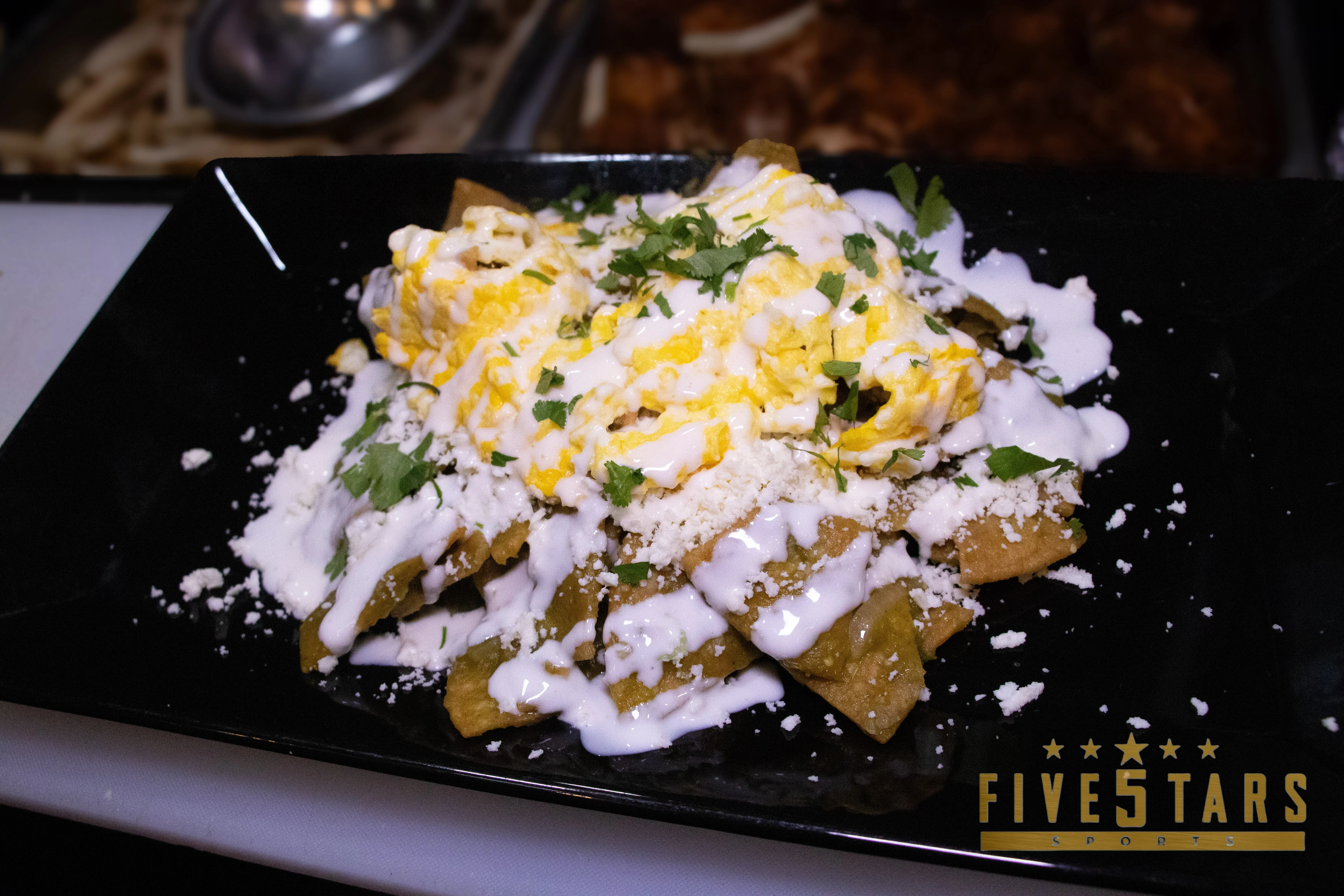 Plate of Mexican chilaquiles topped with crema and cheese