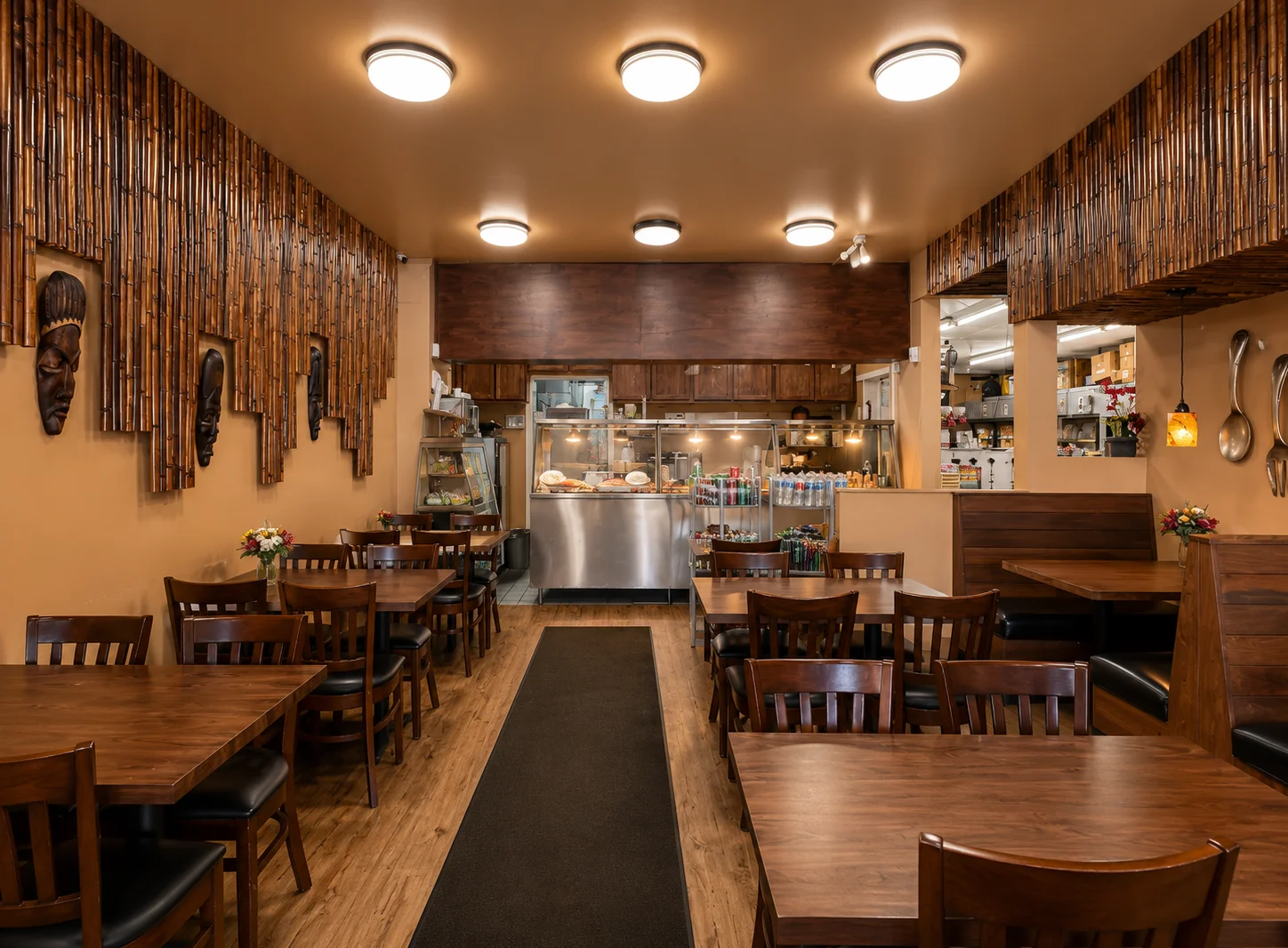 An indoor dining area featuring wooden tables and chairs with a warm ambiance. The walls are decorated with wooden paneling and masks, adding a cultural touch to the restaurant.