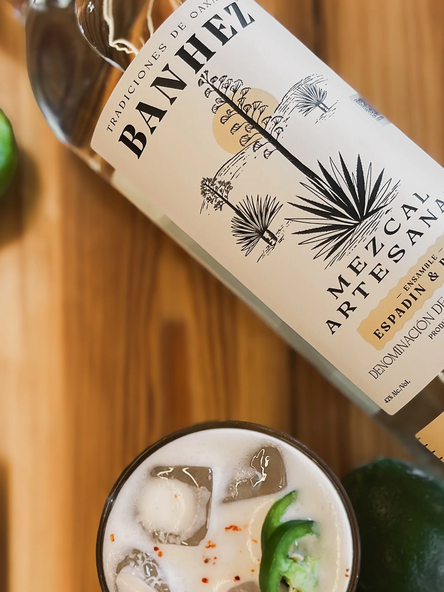 Cocktail with mezcal, lime, and jalapeño on a wooden table.