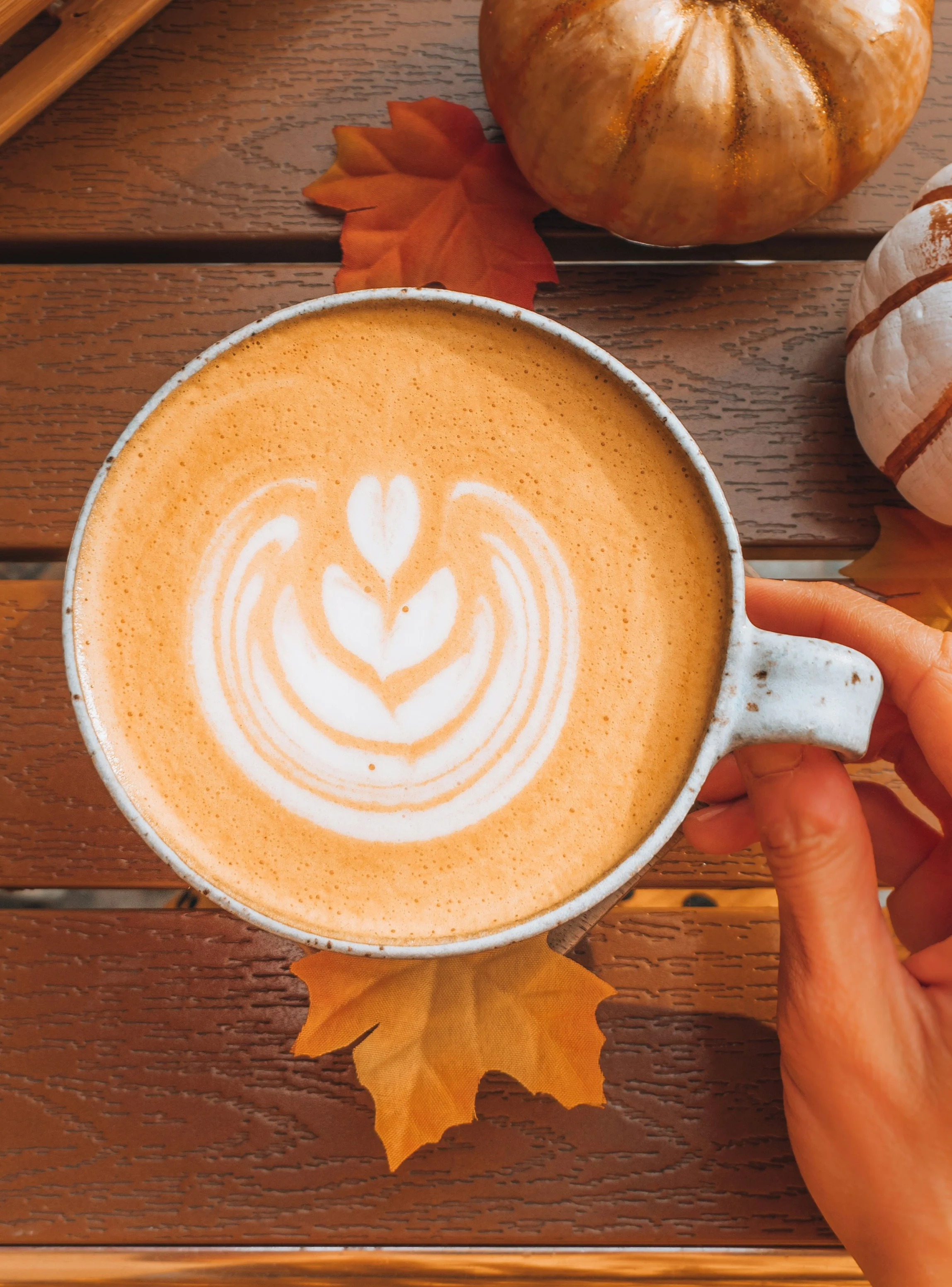 Pumpkin spice latte with latte art on a wooden table