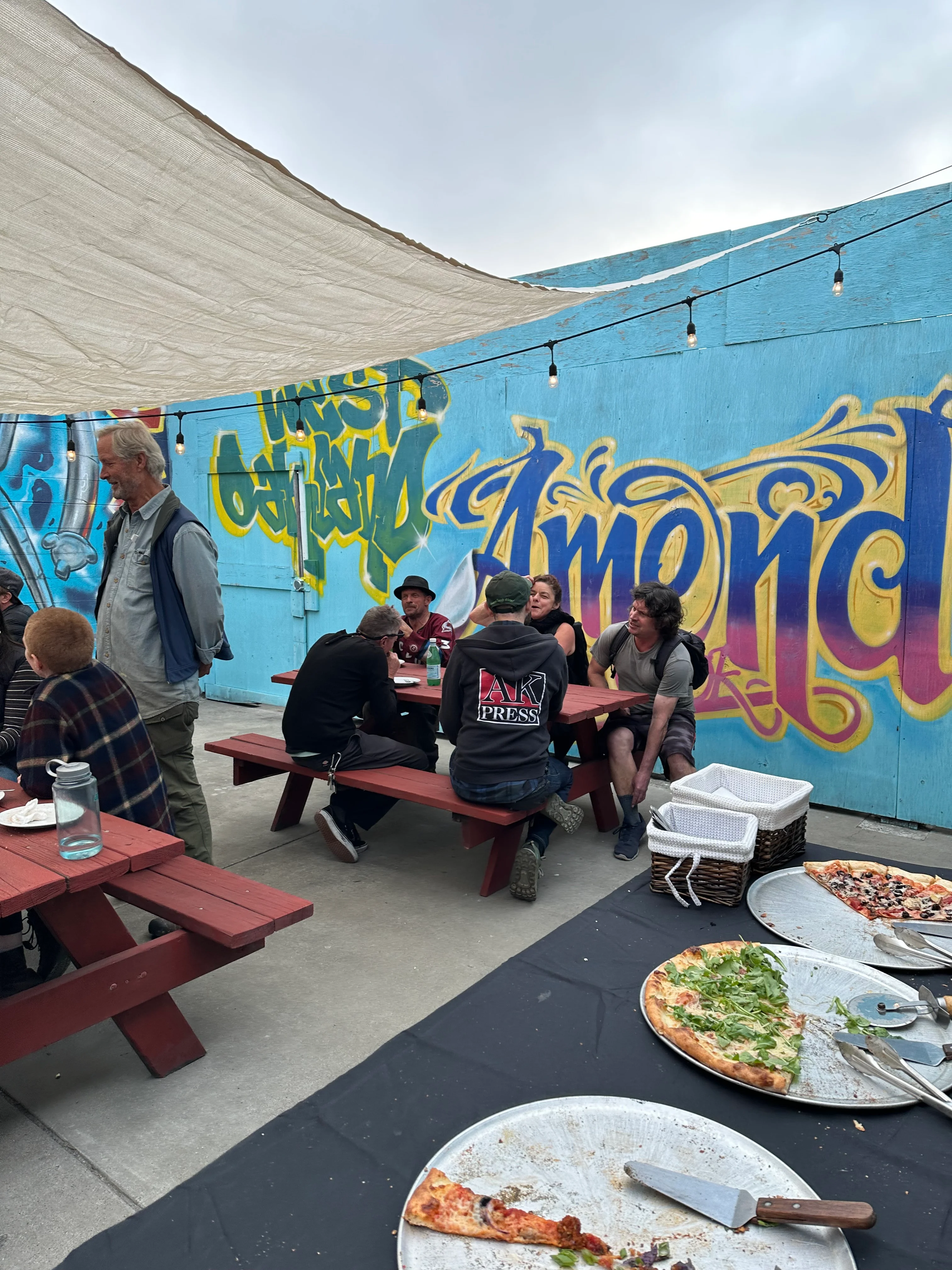 Outdoor dining area with colorful graffiti and pizza platters