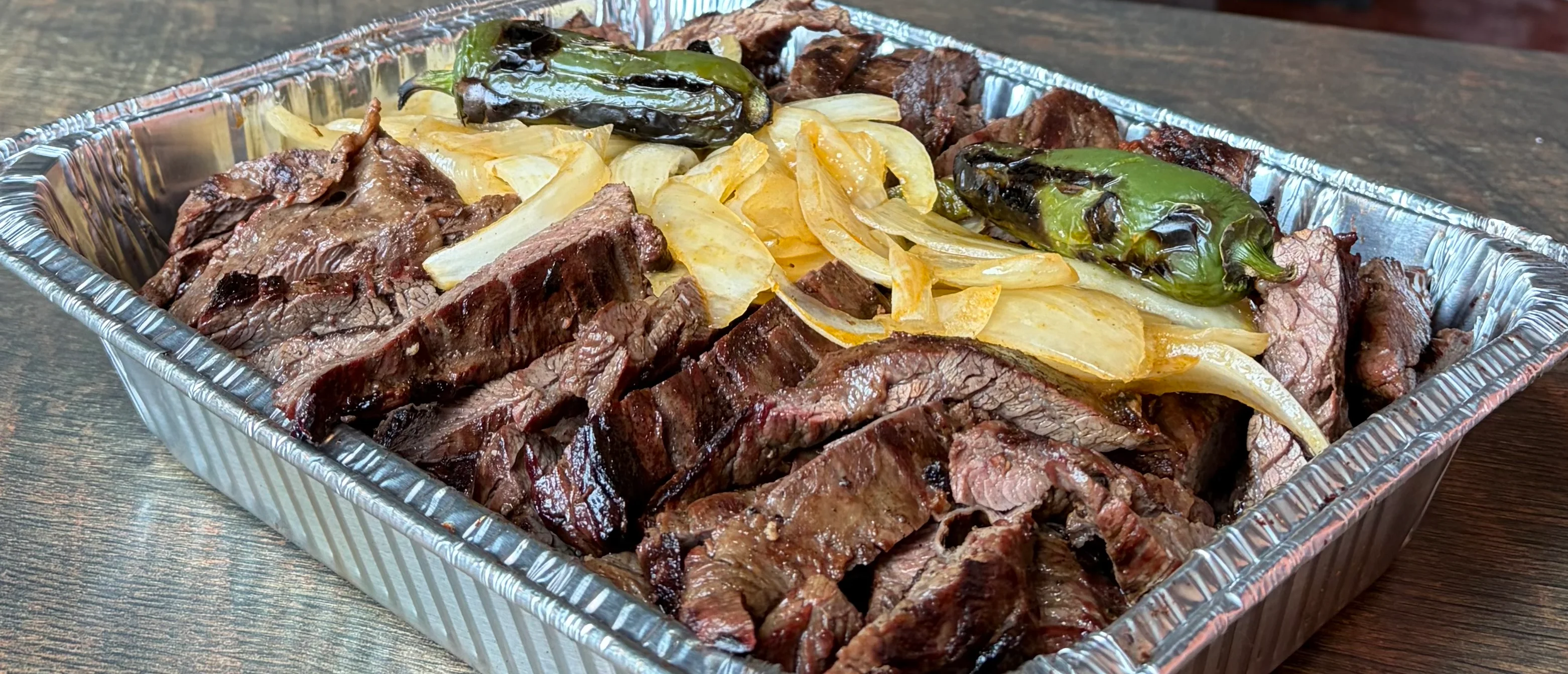 Delicious beef catering platter with assorted sides and garnishes.
