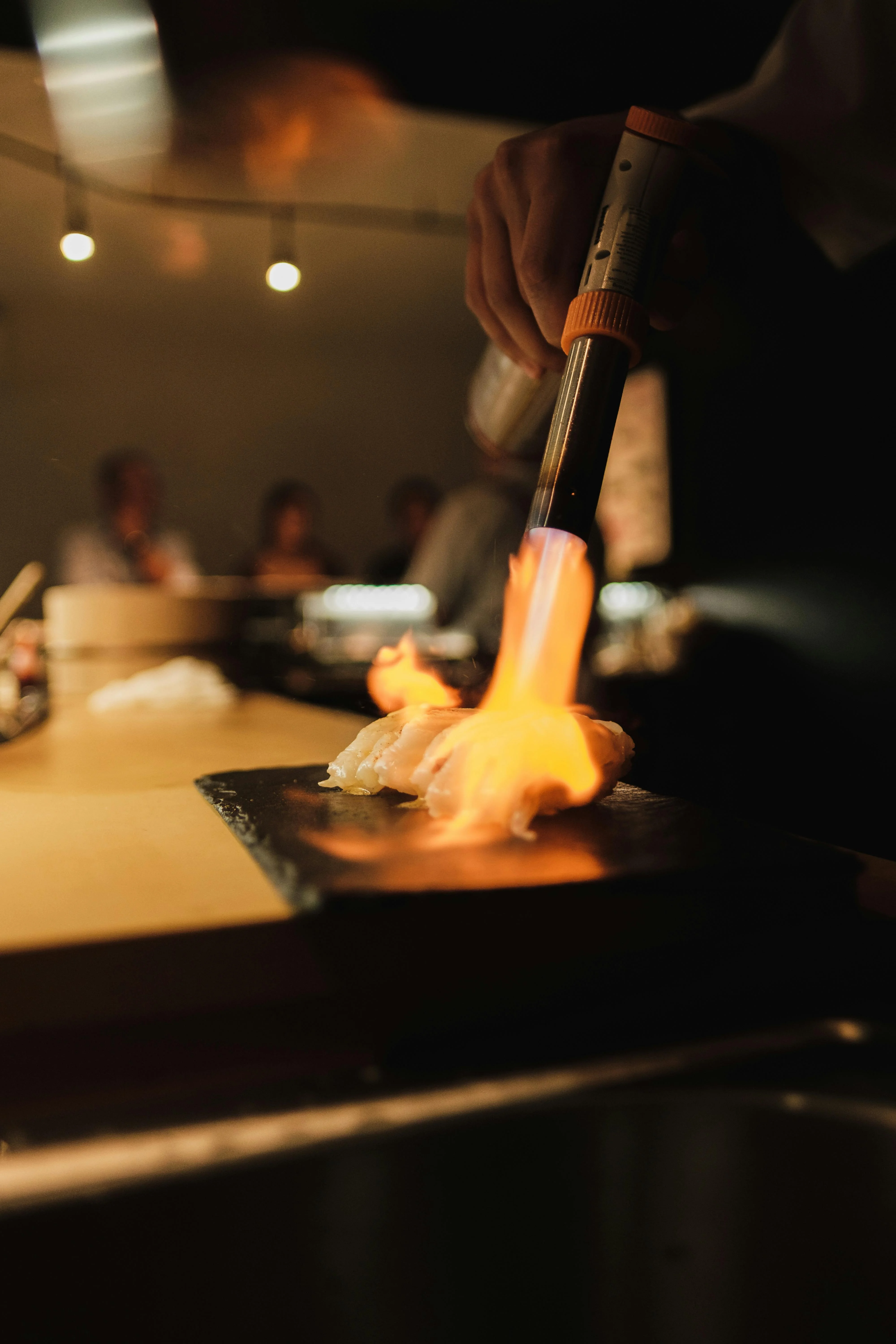 Chef using a torch to sear sushi in a Japanese restaurant