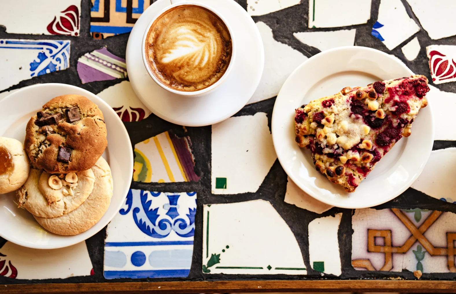 Artisan coffee and pastries on a colorful tiled table