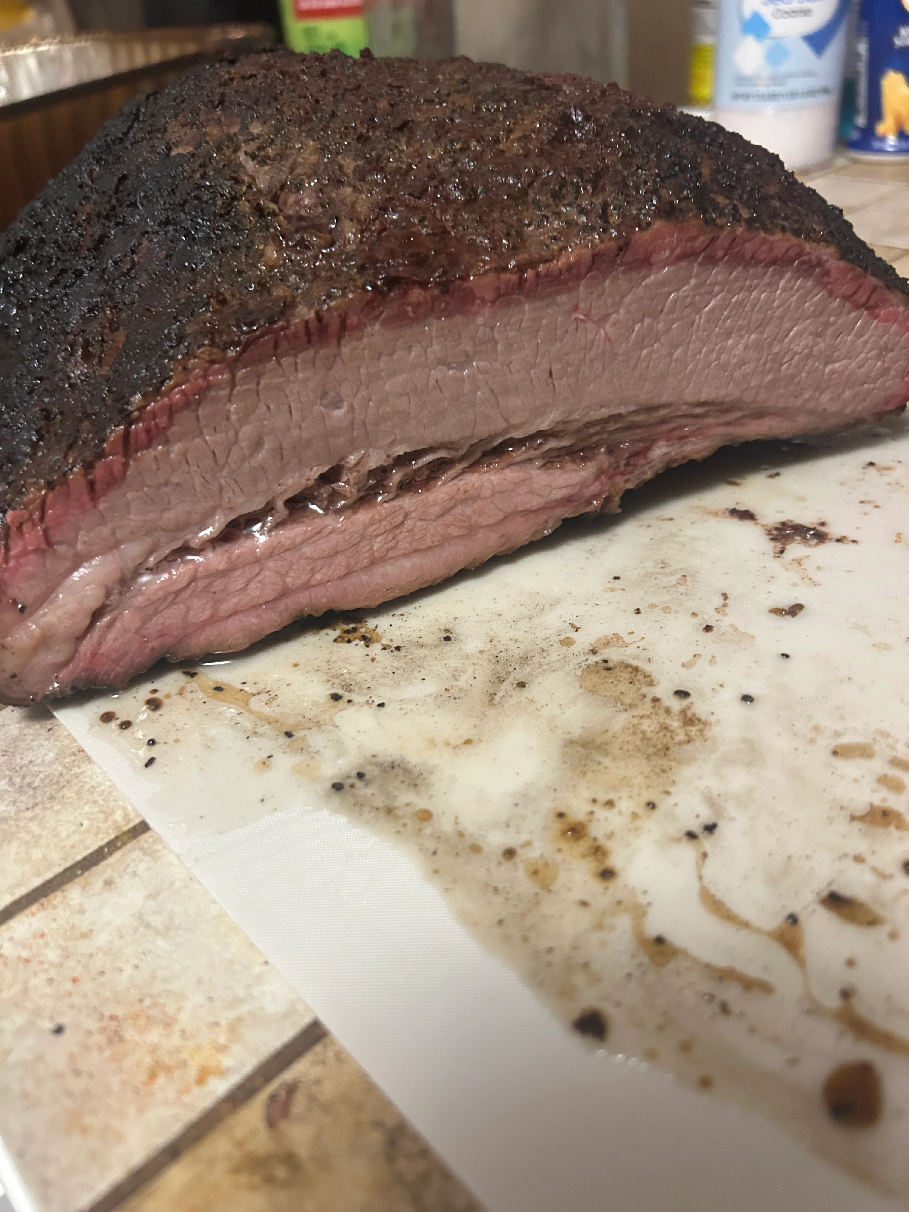 A close-up of a smoked brisket, revealing a tender pink interior and a well-cooked exterior on a cutting board.