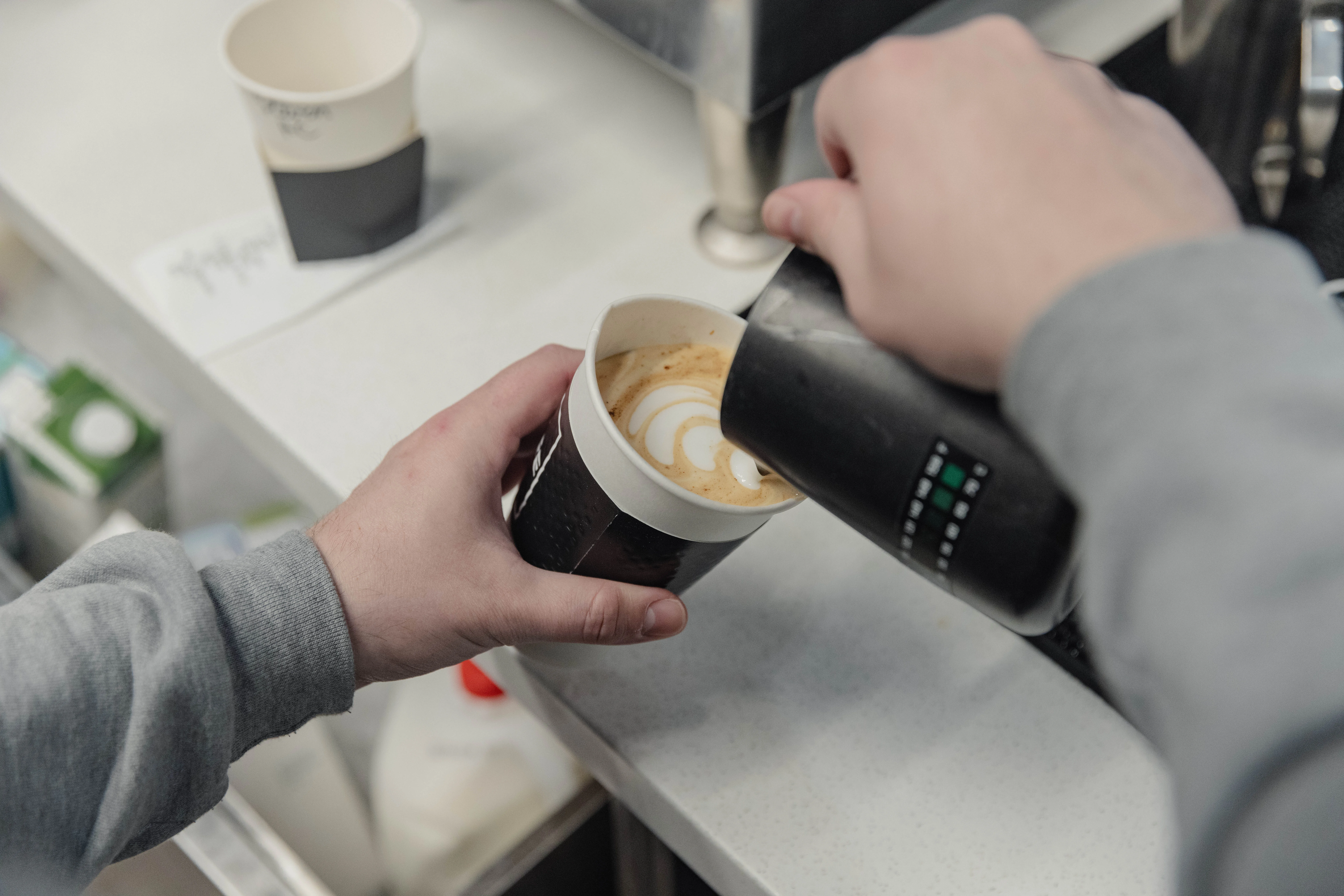 Barista pouring latte art into a coffee cup